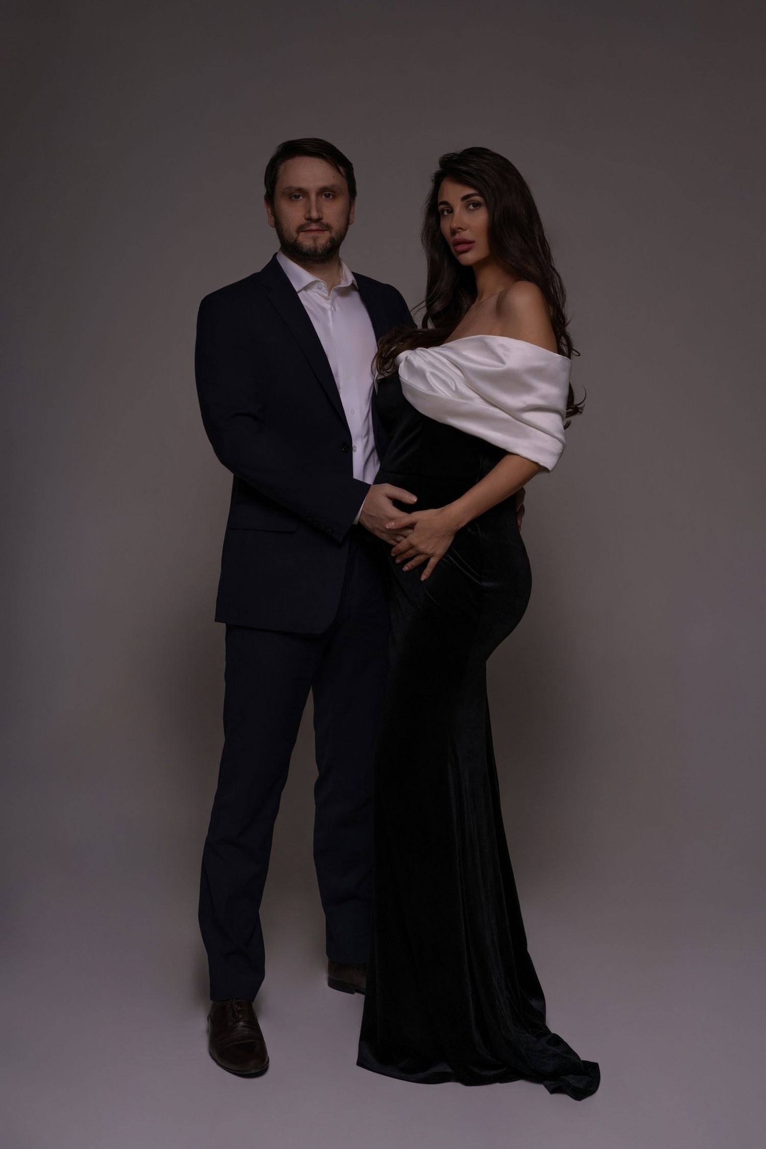Maternity photo of an expecting couple sharing an intimate moment in elegant outfits in photo studio in Chicago.