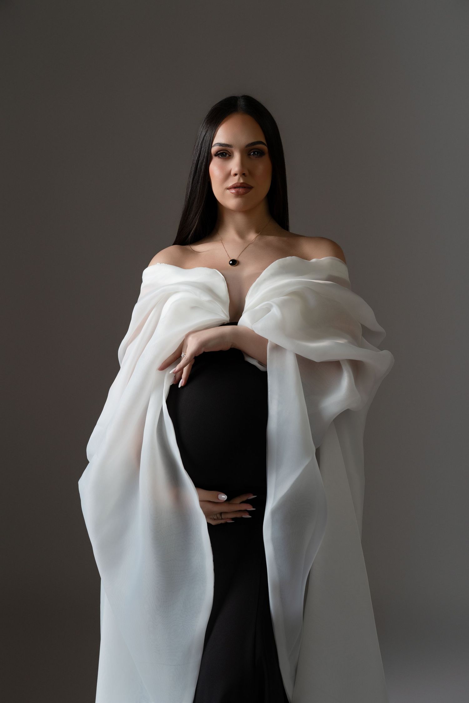 Refined and luxury maternity look featuring a pregnant woman in a white and black couture-style dress during her Chicago studio session.