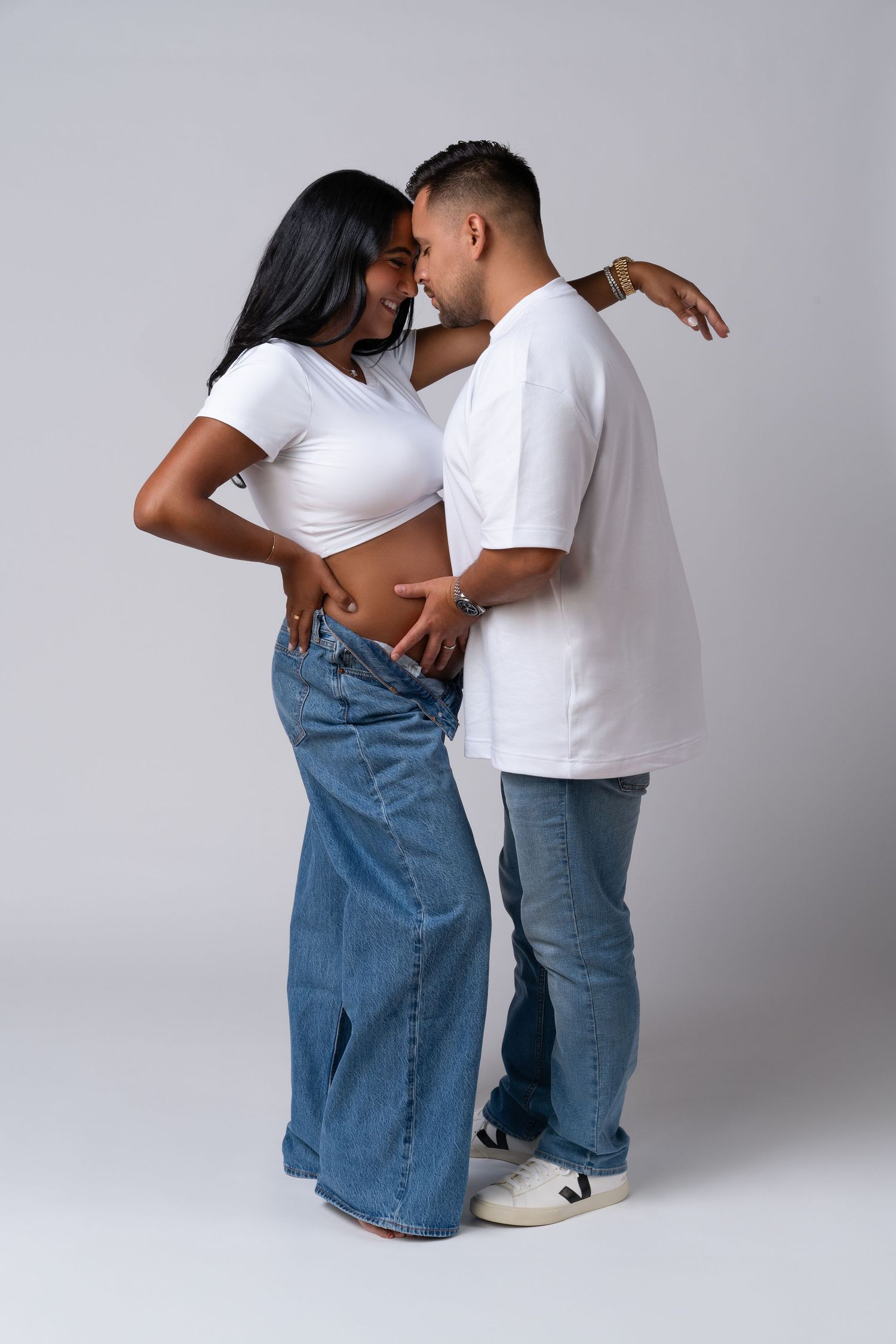 Maternity couple photoshoot in Chicago studio of maternity photographer — couple in jeans and white t-shirts.