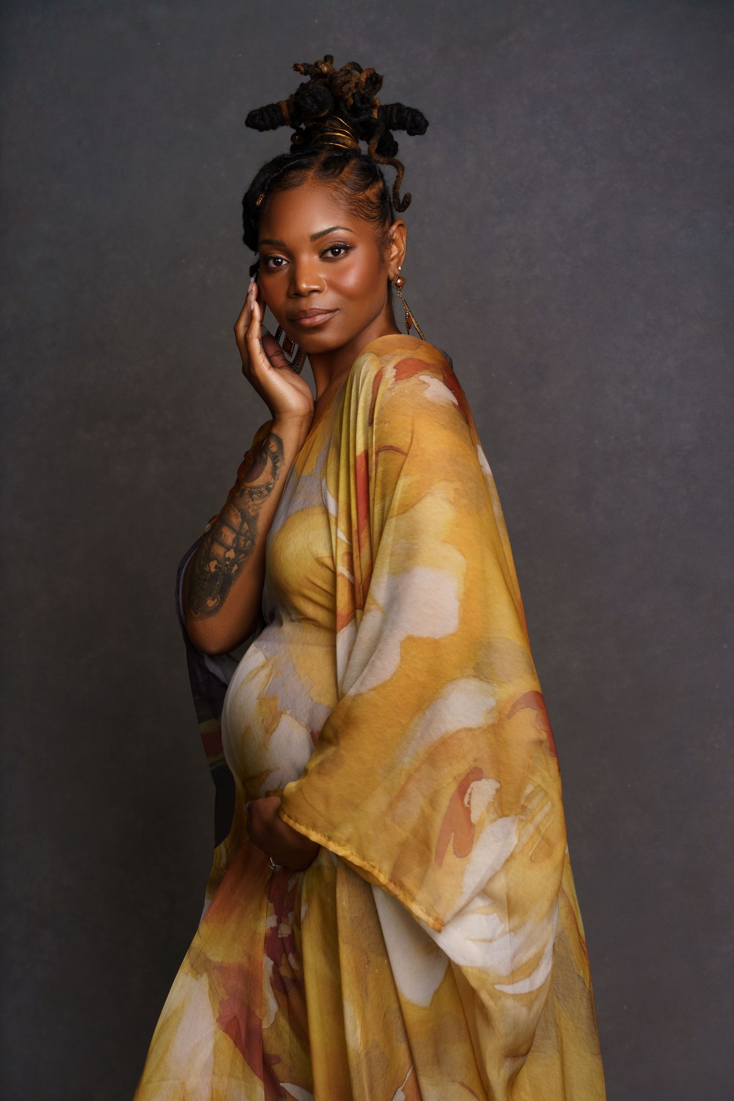 African American mom-to-be in a long ethnic dress with traditional hairstyle — powerful and cultural maternity portrait in a Chicago studio.