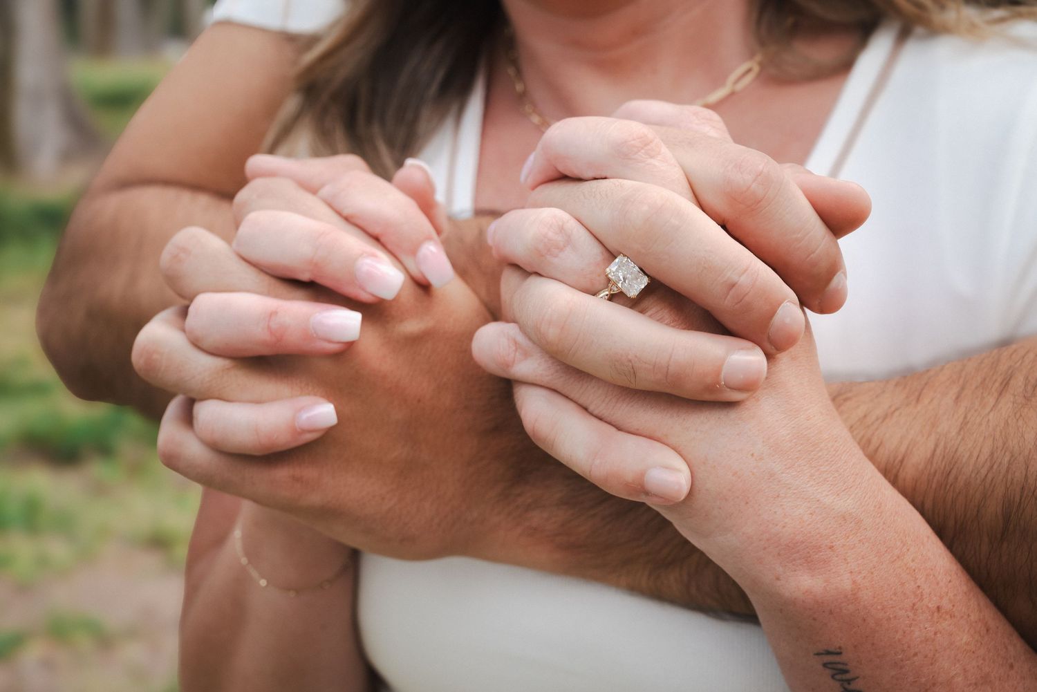 Close-up of couple holding hands showing an elegant diamond engagement ring, symbolizing love and commitment.