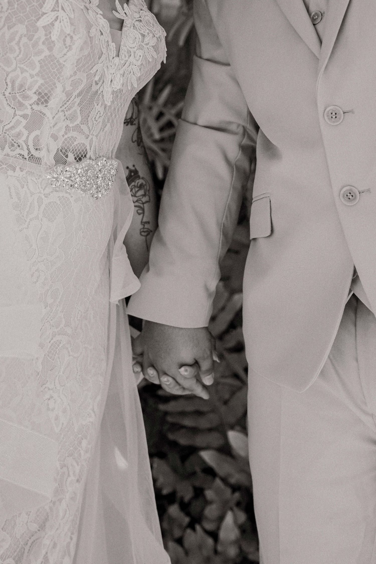 Close-up detail shot of a light gray suit jacket with button and pocket showing a formal wedding attire aesthetic.