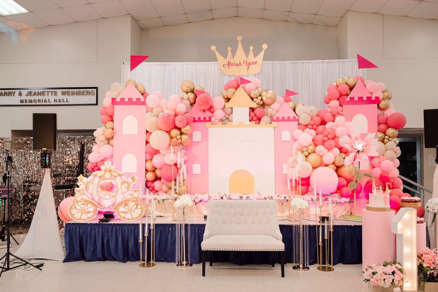 Pink princess castle balloon backdrop with gold crown topper for a glamorous birthday party celebration.