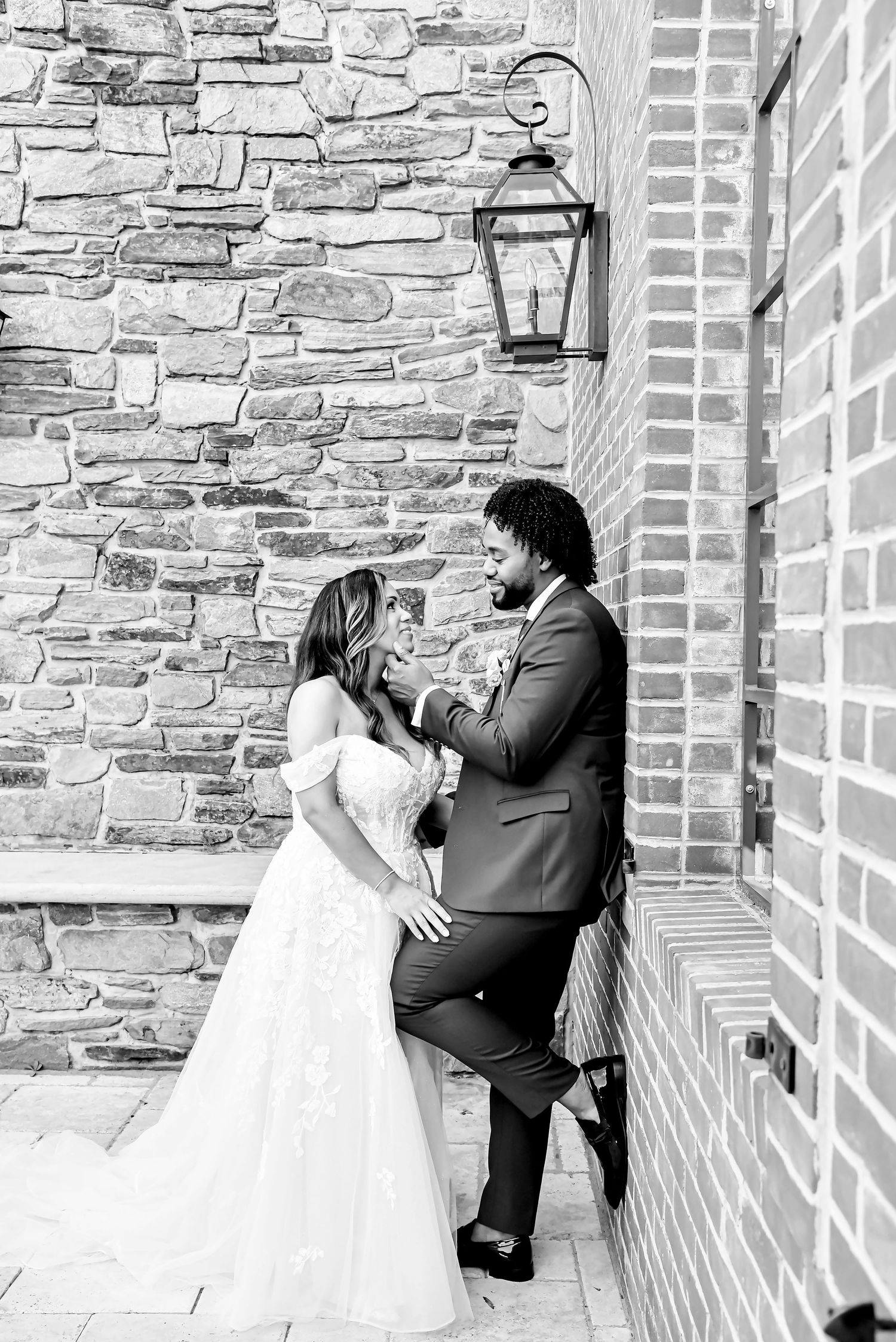 A romantic black and white photo series showing a couple in formal attire embracing against a stone wall.