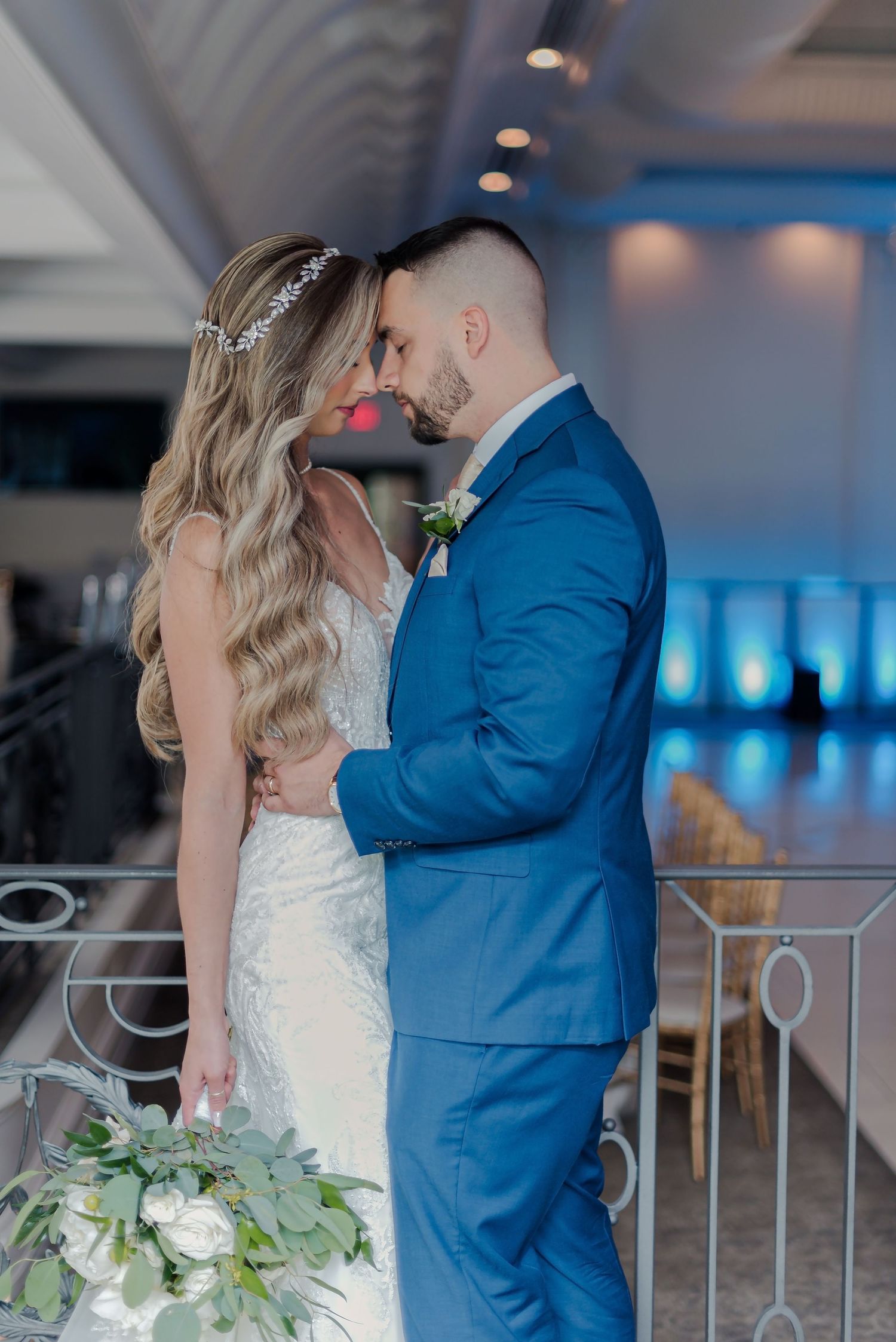 A romantic wedding moment at a venue with blue lighting, featuring a white dress and royal blue suit.