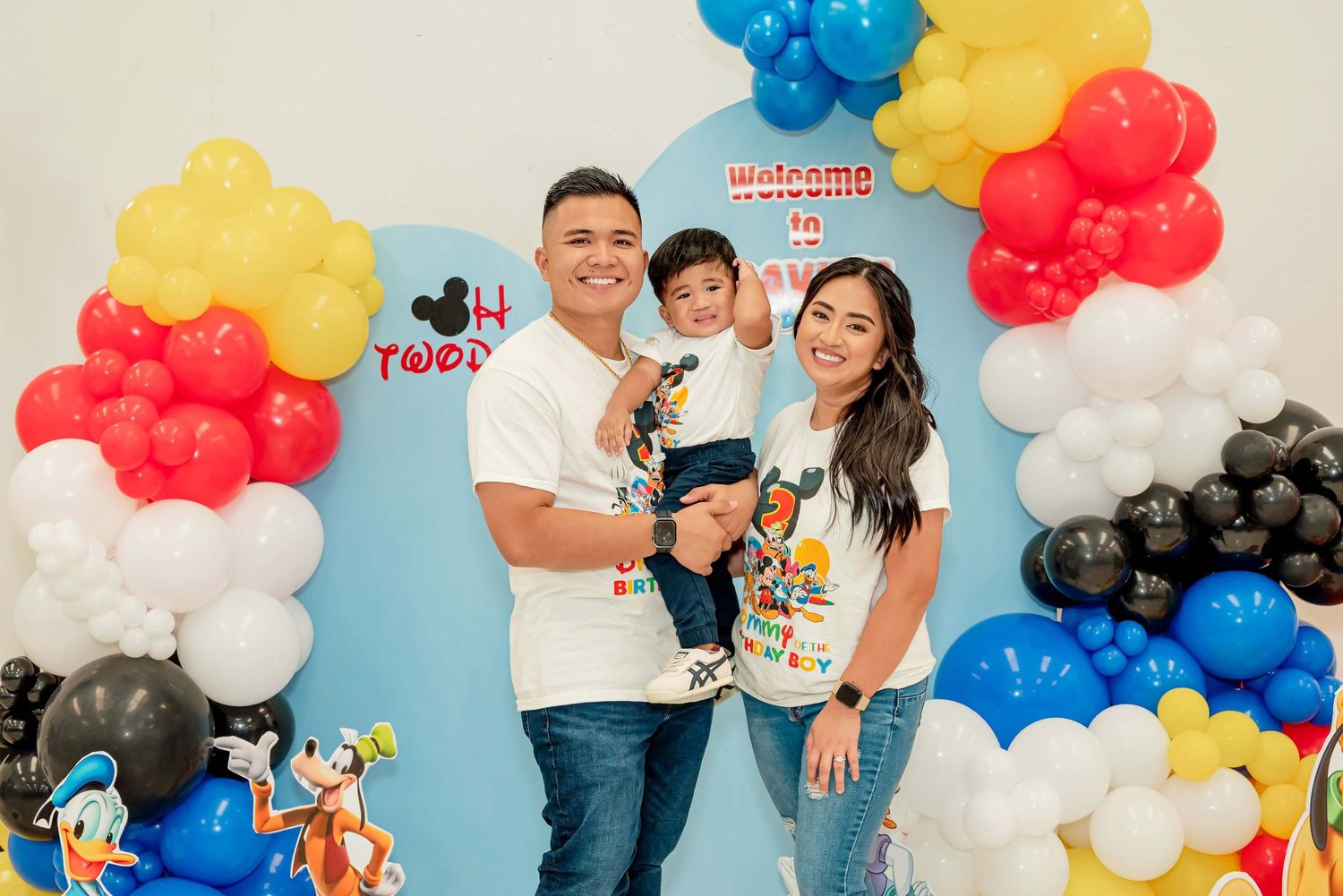 Birthday party scene with colorful balloon garland arrangements in blue, red, white and yellow with Disney decorations.