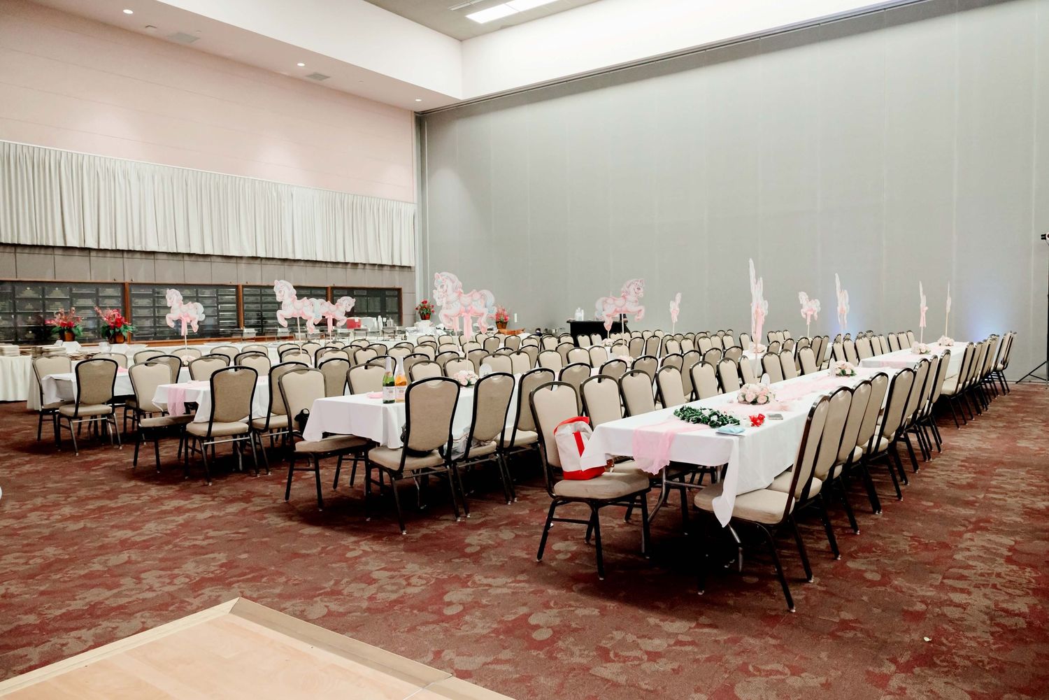 Elegant banquet hall with rows of chairs and white tablecloths, set up for a formal event or conference.
