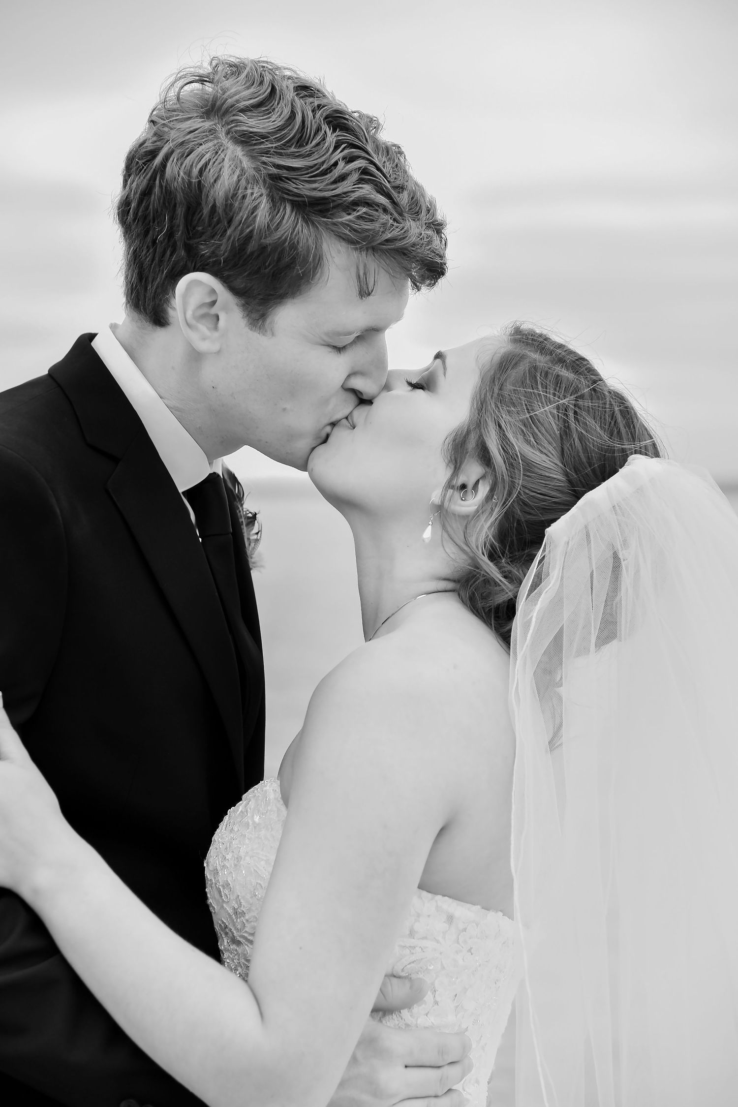 A romantic black and white wedding photo sequence showing a couple sharing a tender kiss during their ceremony.