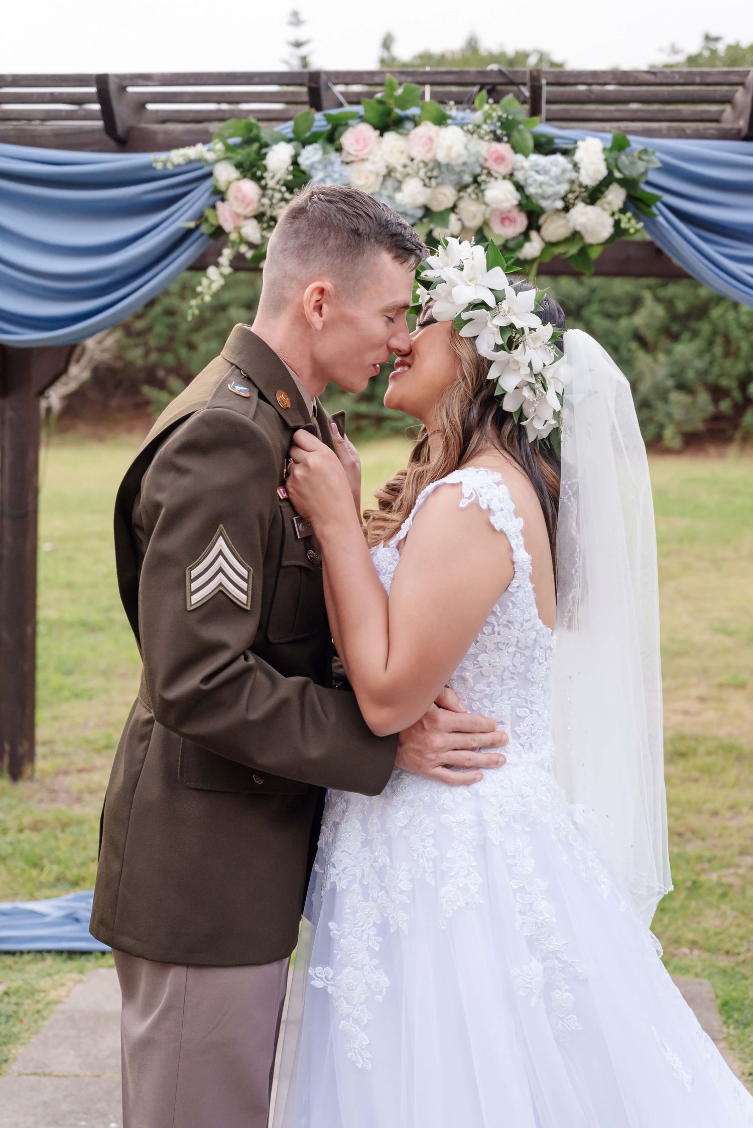 A romantic wedding photo sequence showing a couple sharing their first kiss under a blue and floral decorated arch.