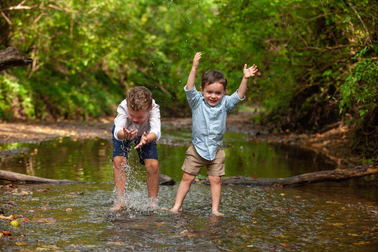 Children splash and play in a shallow creek on a sunny summer day during an outdoor adventure.
