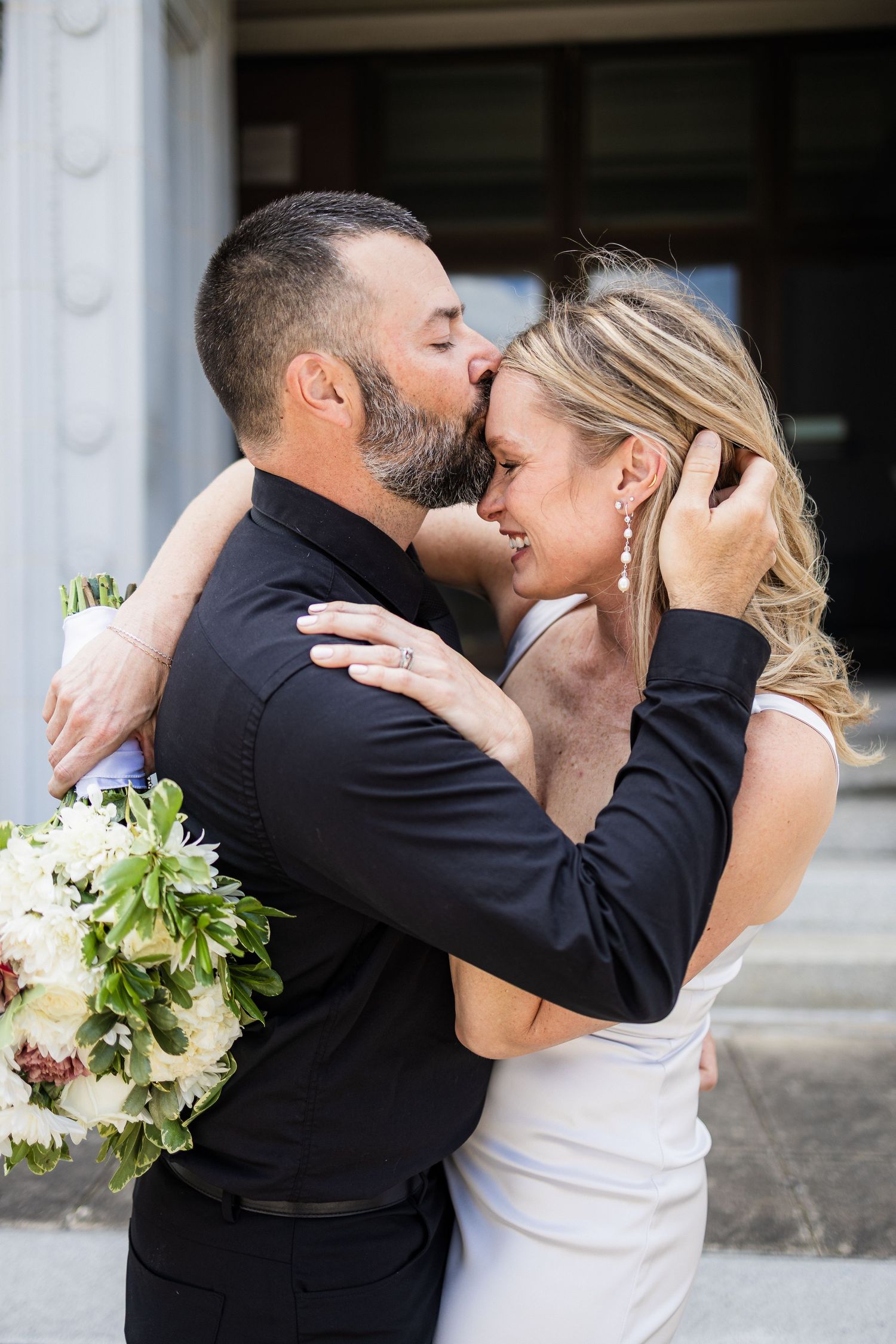 A couple shares a romantic kiss during their wedding day, with white flowers and formal attire captured in multiple frames.