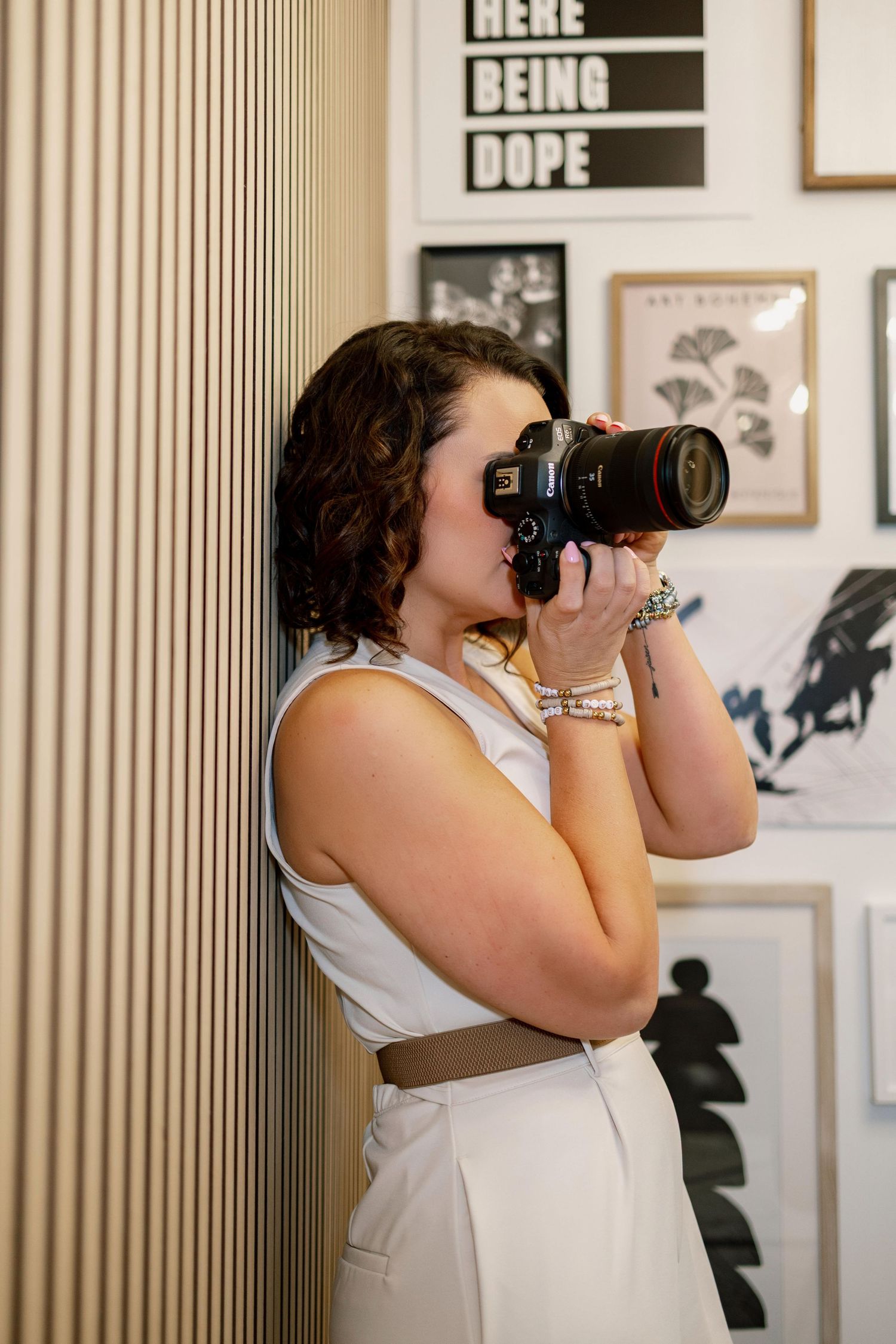 Professional photographer in white top taking photos against striped wall background.