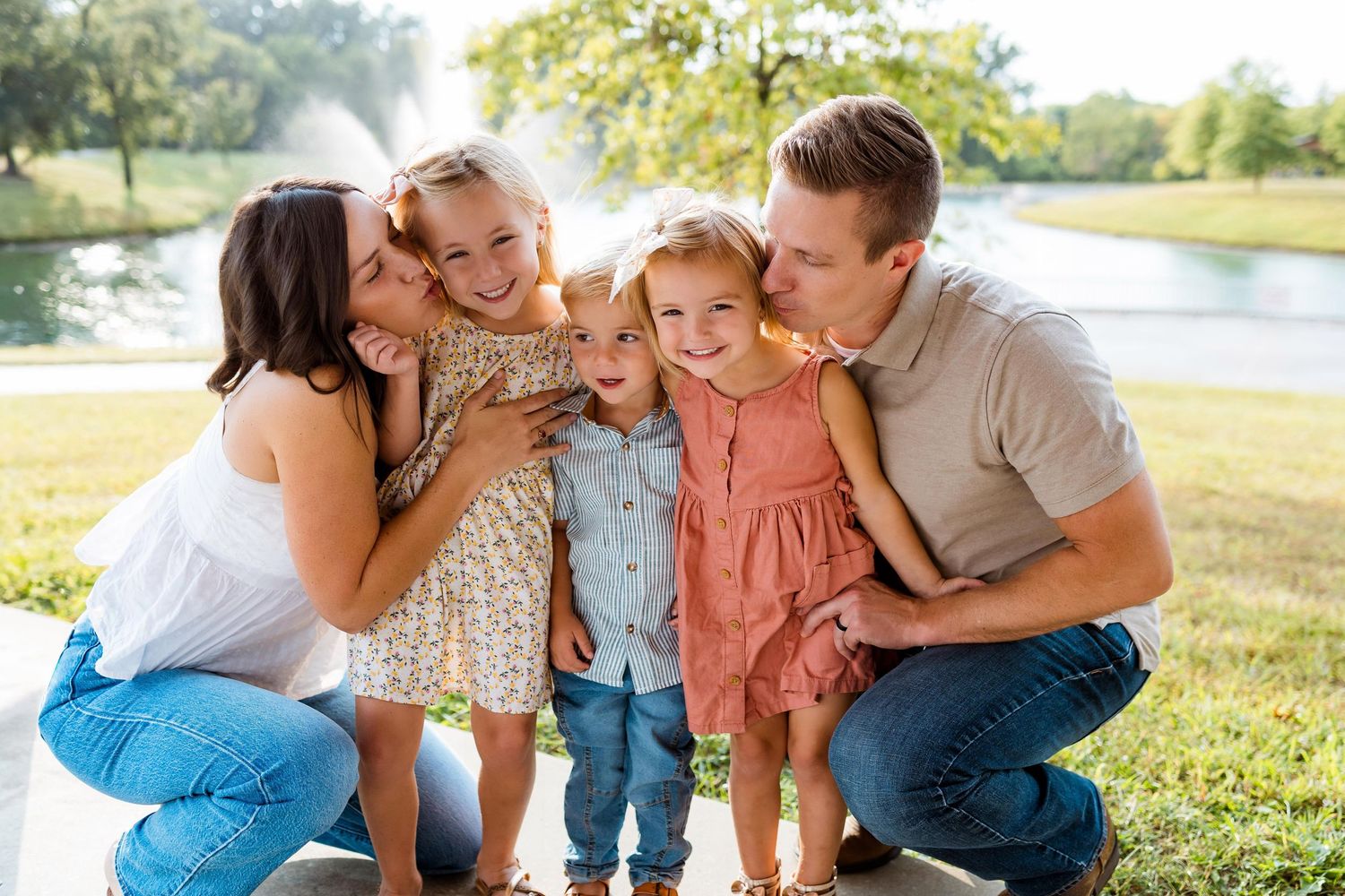 Family enjoying a playful moment together outdoors on a sunny day in a grassy field.