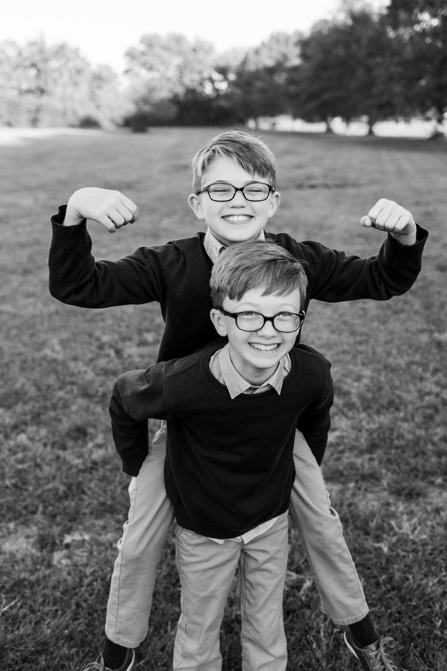 Black and white photos of children playing and posing playfully in matching outfits on grassy field.