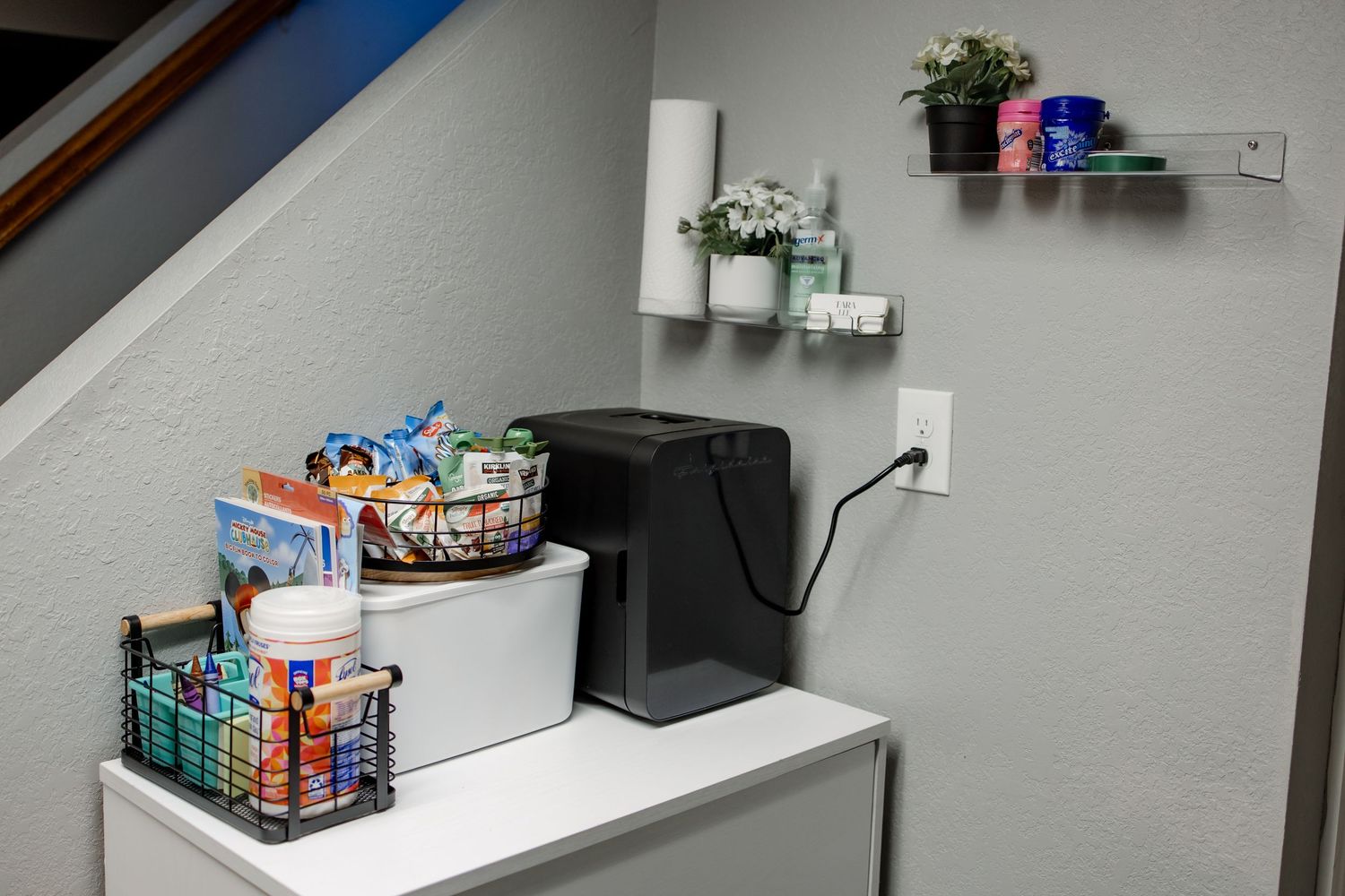 Organized shelving unit displays various snacks and supplies in a modern office break room area.