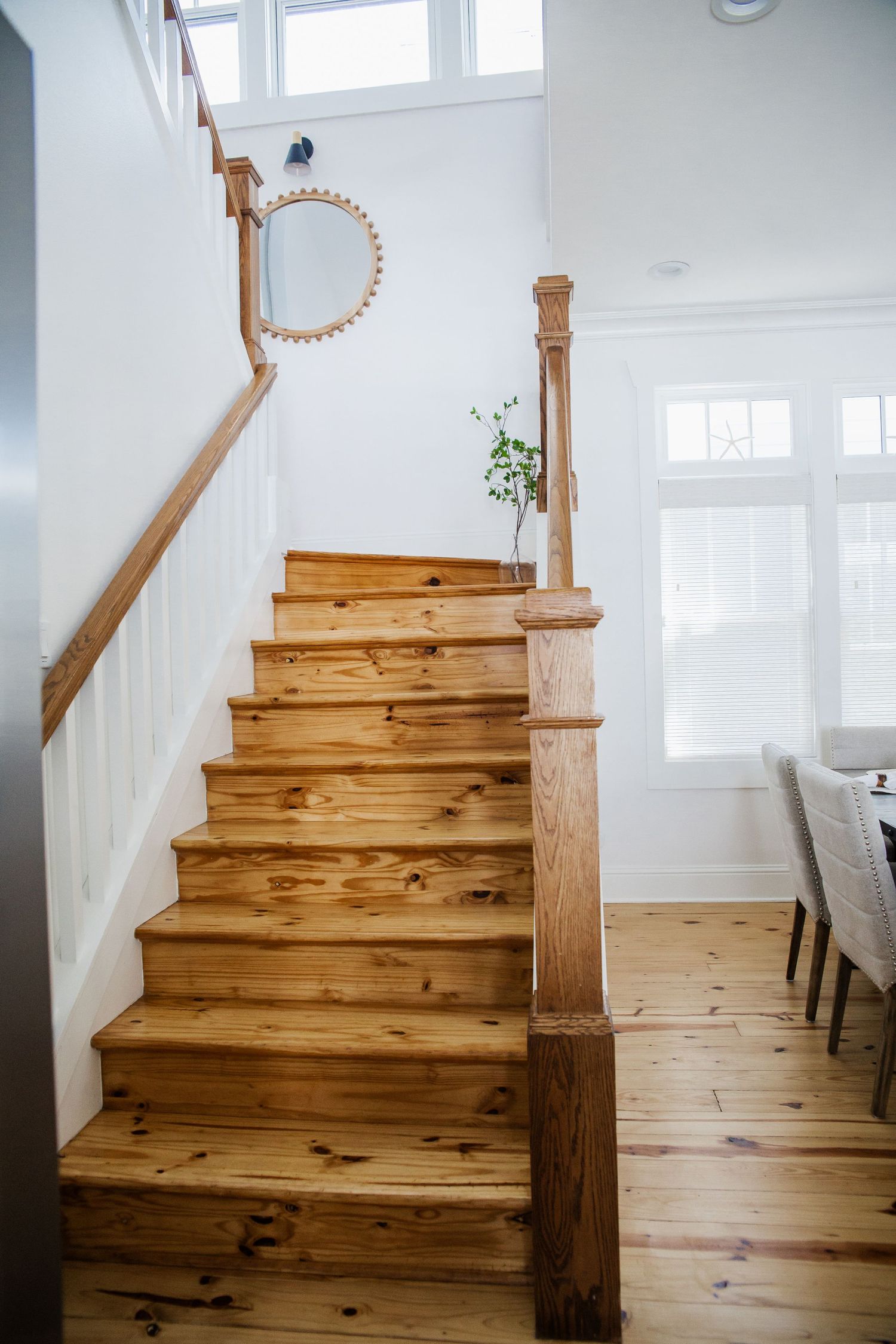 Wooden staircase with white walls and natural light from windows.