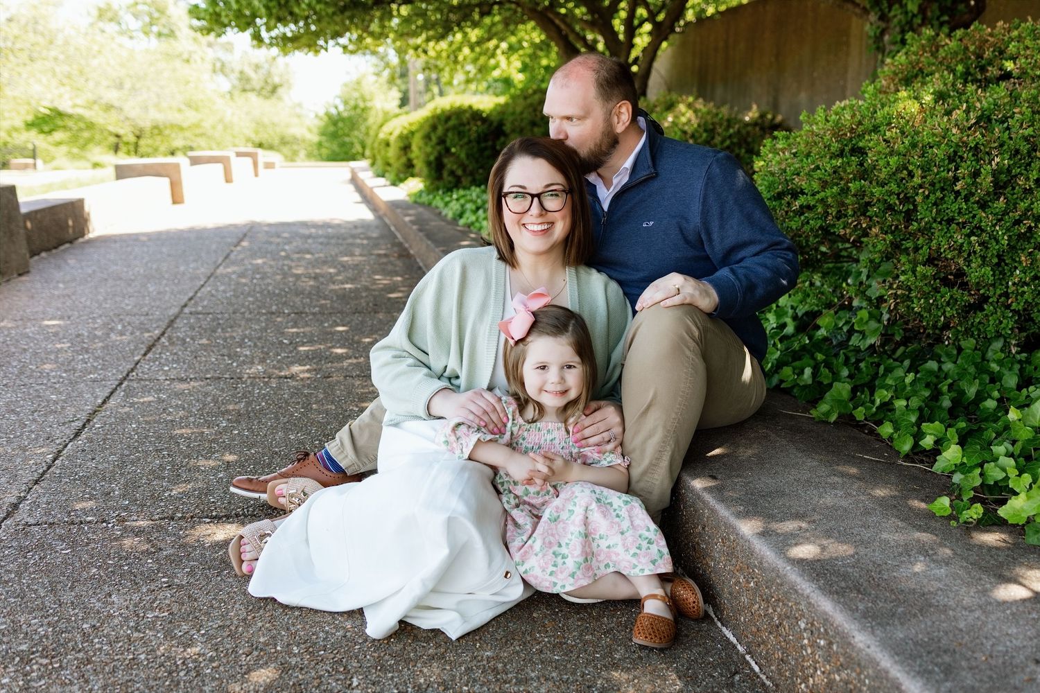 Parents cuddling their young daughter during a relaxed family portrait session in the Edwardsville area