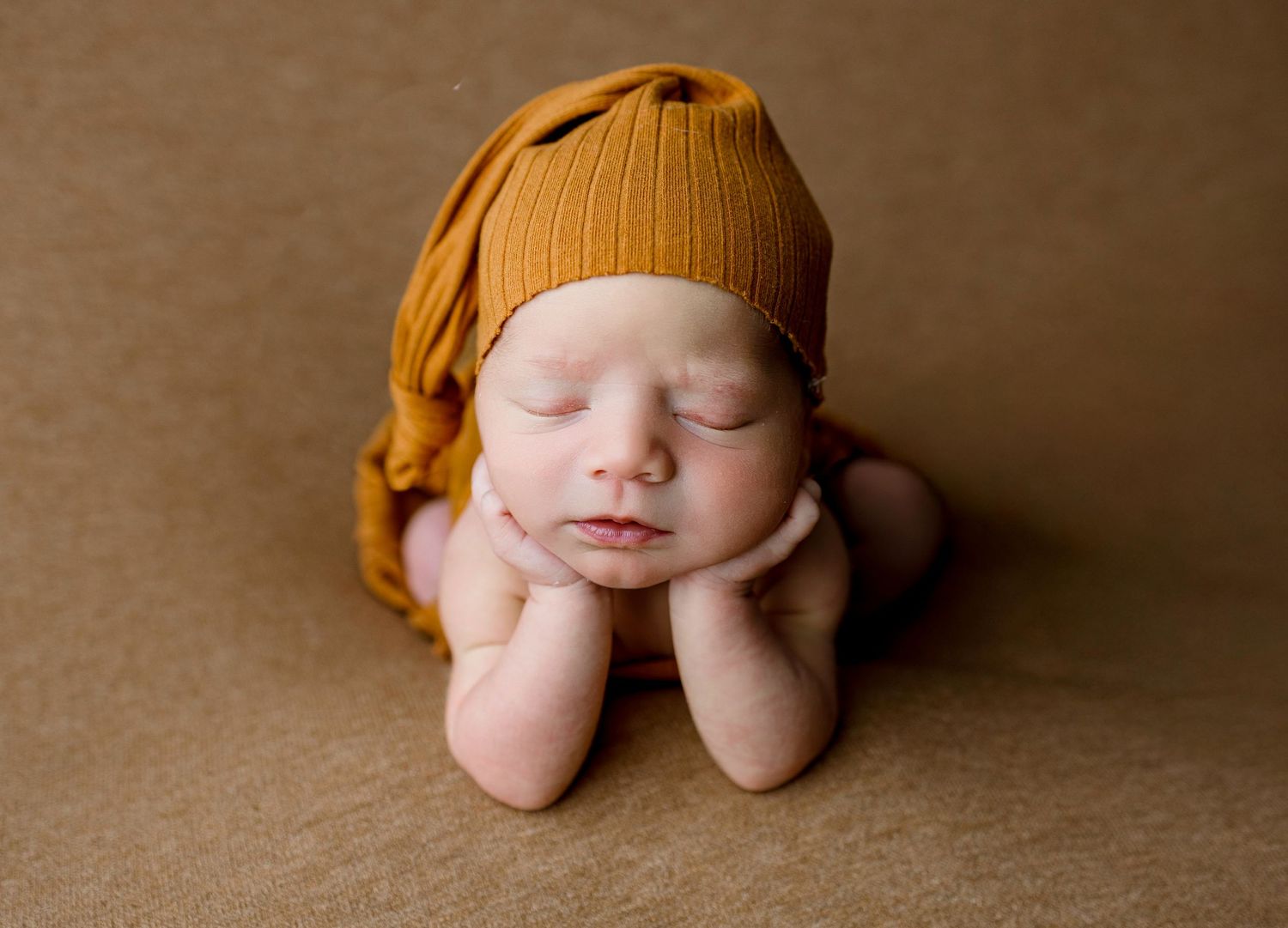 A peaceful sleeping newborn nestled in warm brown tones during a professional photo session.