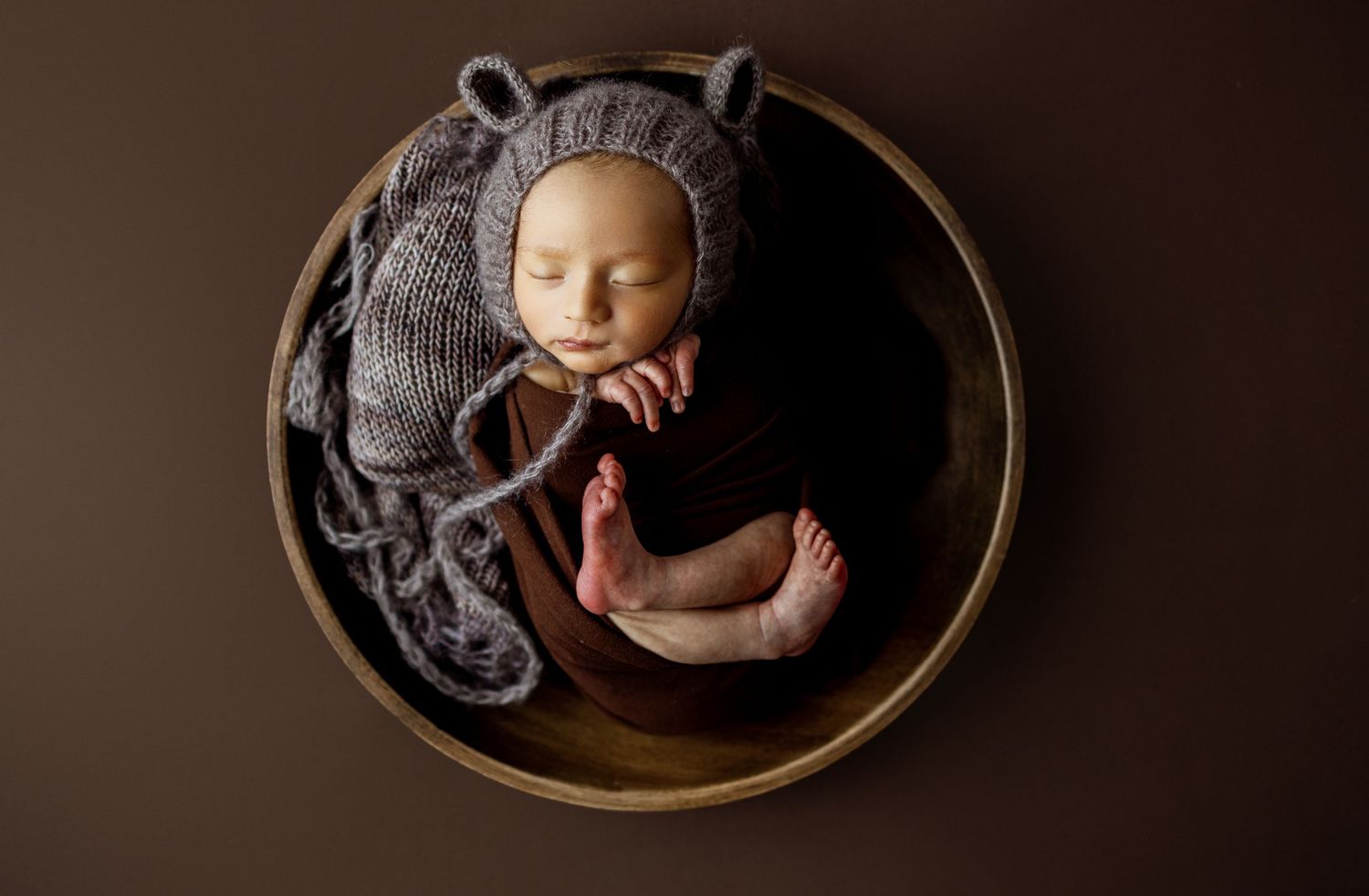 A series of circular framed photos showing a sleeping newborn baby in various artistic poses on dark backgrounds.