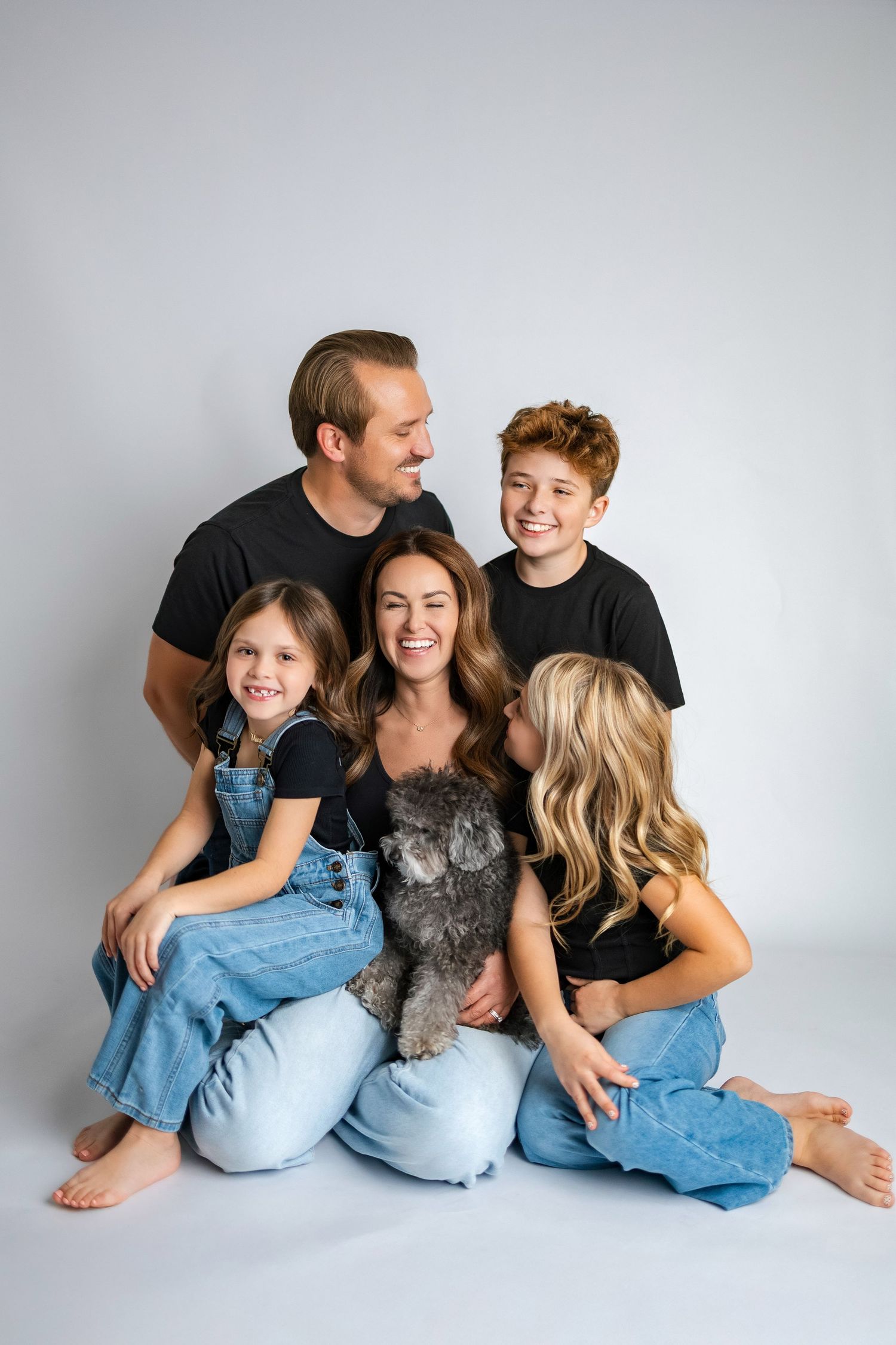 A casual family photo session showing playful moments against a light gray studio backdrop.