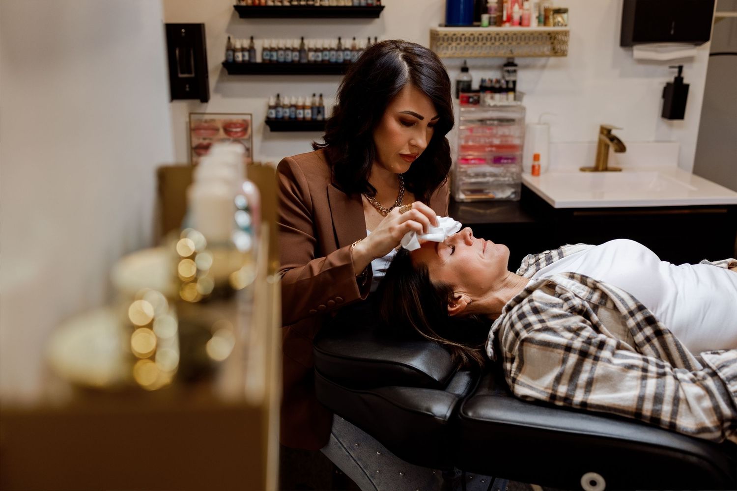 Spa technician performs facial treatment on client while wearing protective gloves in luxurious wellness setting.