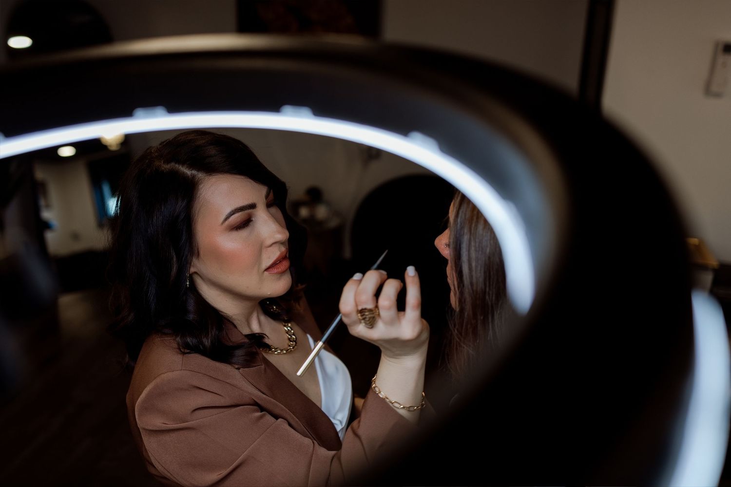 A person takes a sip from a glass while sitting in a dimly lit room with a moody atmosphere.