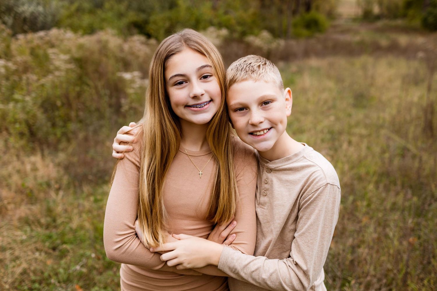 Affectionate couple shares tender moments in a field during golden hour photography session.