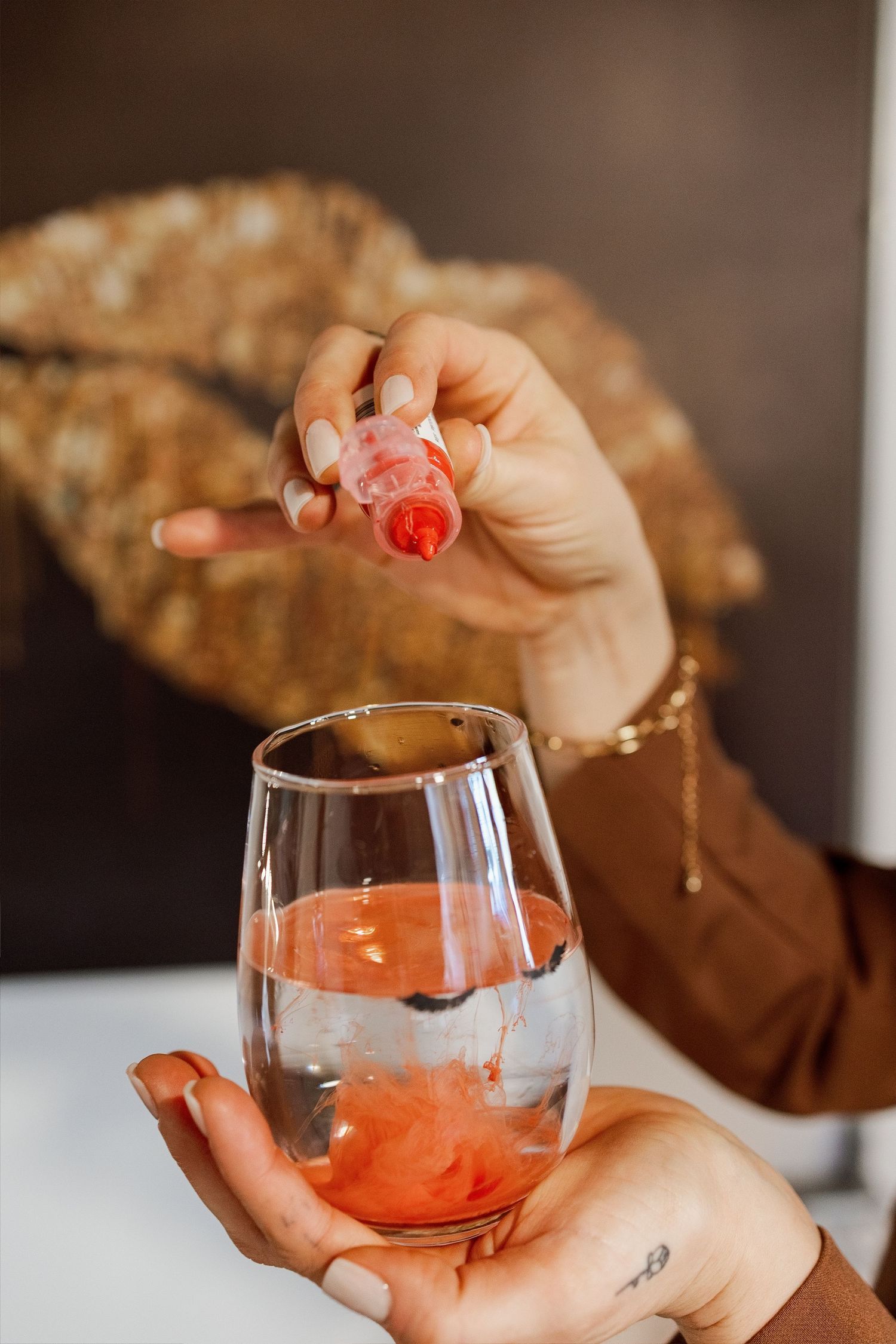 A sequence of hands dropping red gummy bears into a glass of sparkling wine to create a fun cocktail.