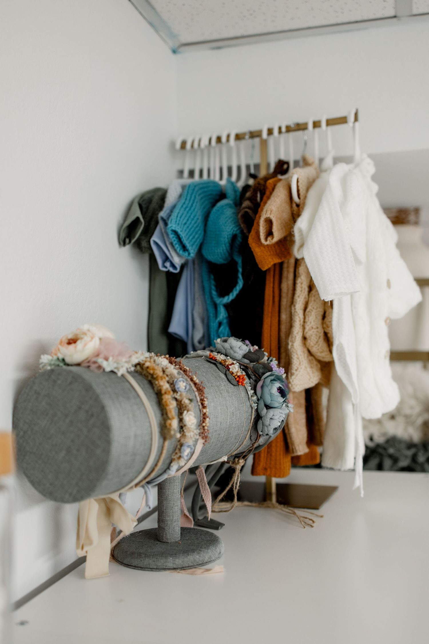 A row of winter hats and scarves displayed on wall-mounted hooks in muted tones of gray, teal, and brown.