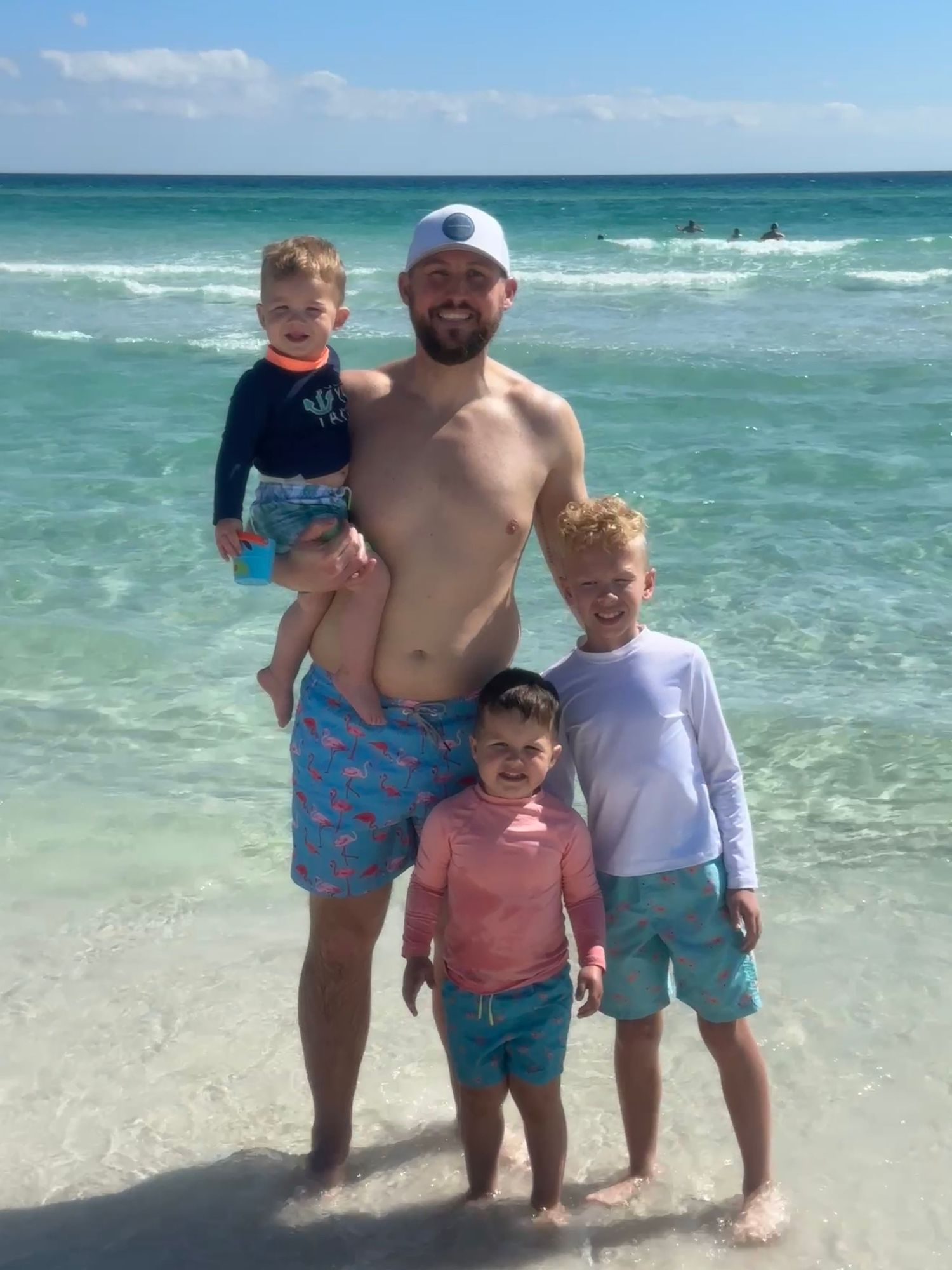 Family enjoying a sunny day at the beach with turquoise waters and white sand.