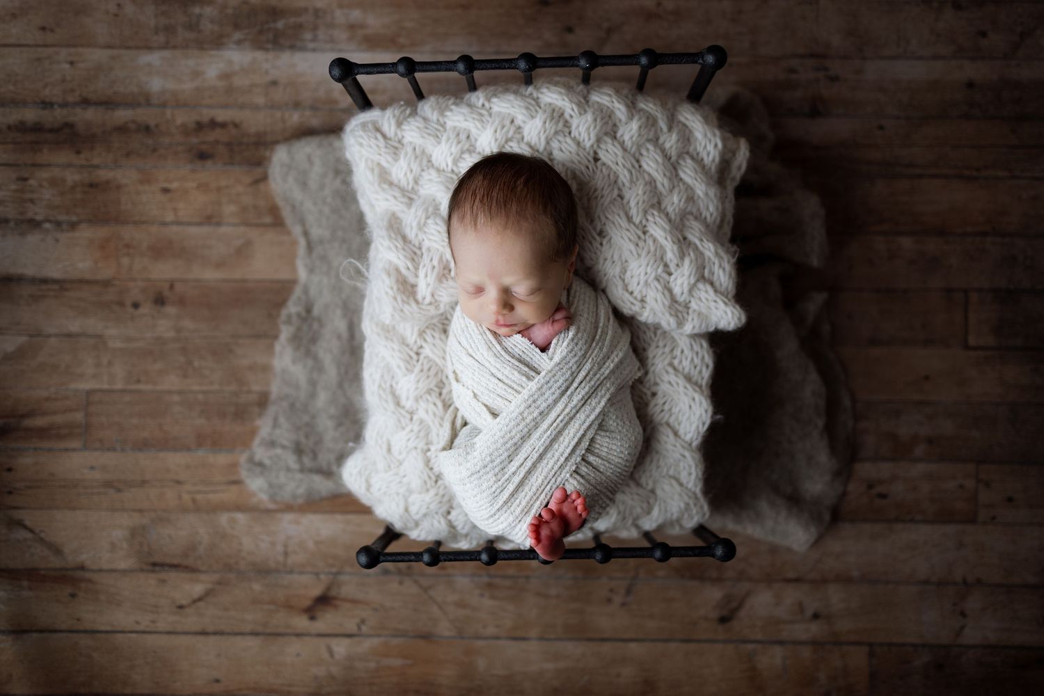 A series of peaceful newborn portraits showing an infant sleeping on white blankets against rustic wooden backgrounds.