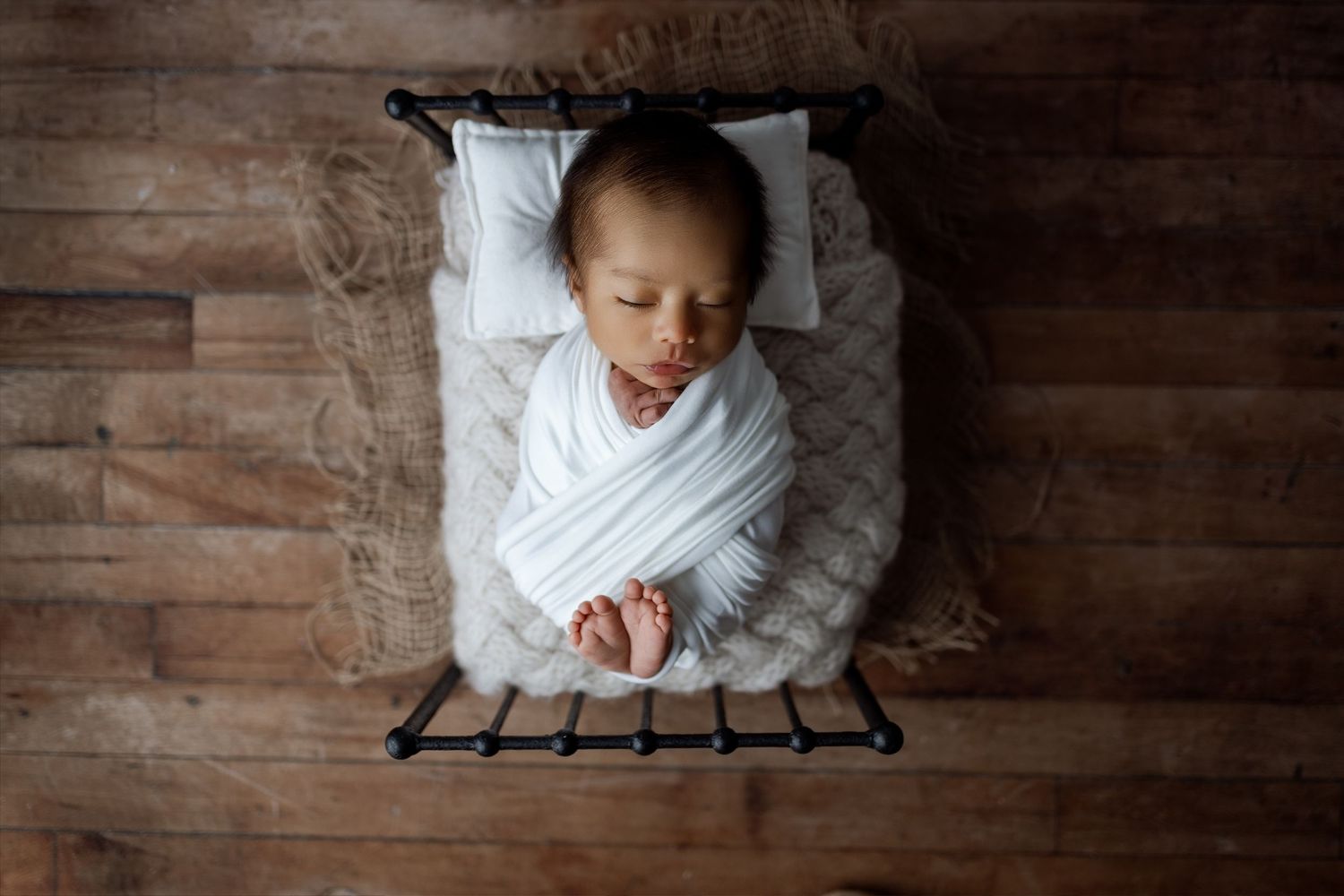 Artistic overhead shots of sleeping newborn in white wrap on rustic wooden backdrop.