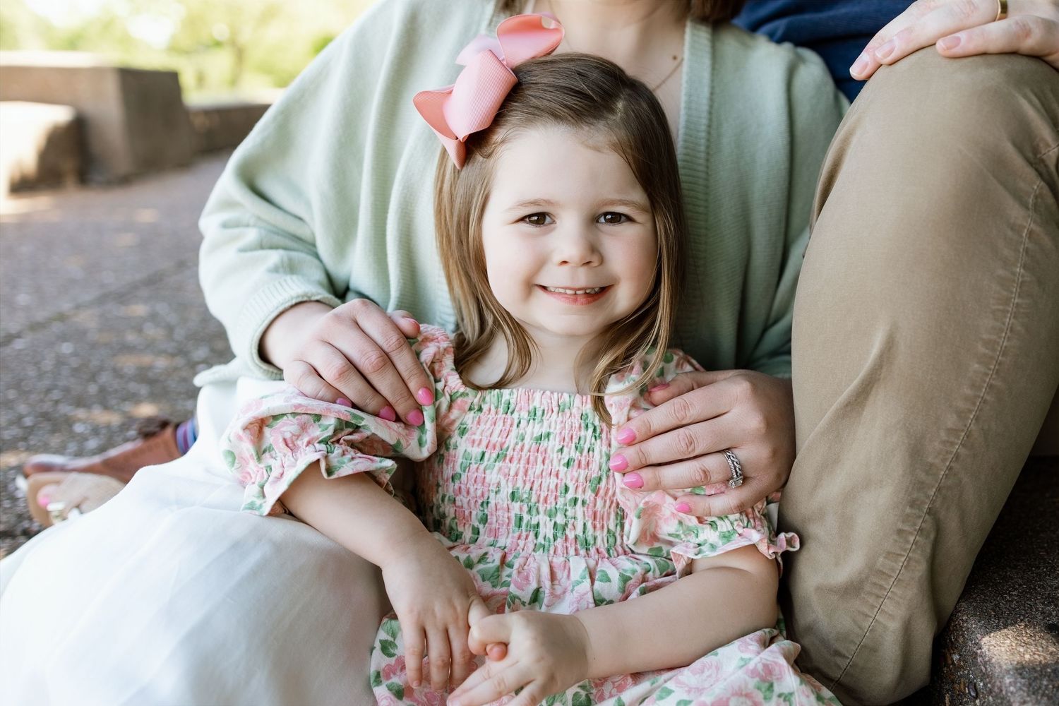 Young girl smiling between family members during a candid outdoor portrait session in Southern Illinois