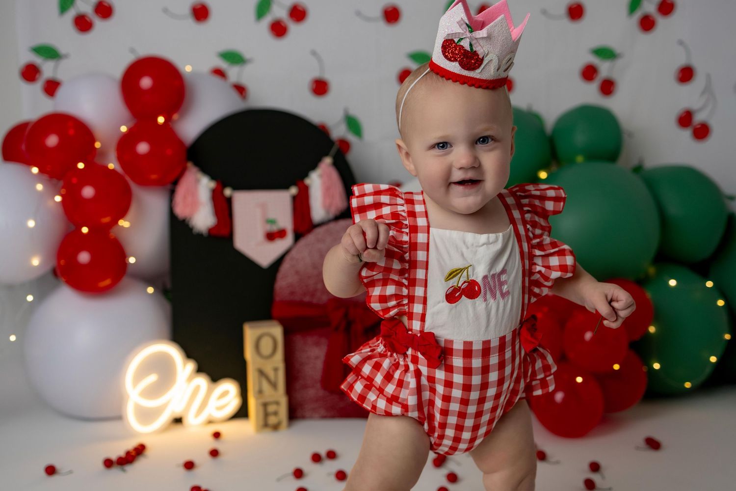 A festive holiday photoshoot setup with red and green balloons, checkered gingham outfits, and Christmas decorations.