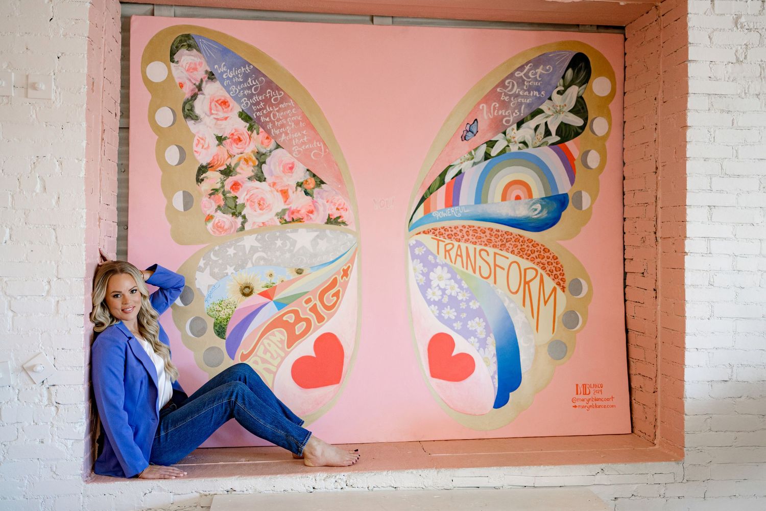 A colorful mural featuring hearts and floral designs painted on a pink wall with inset alcoves.
