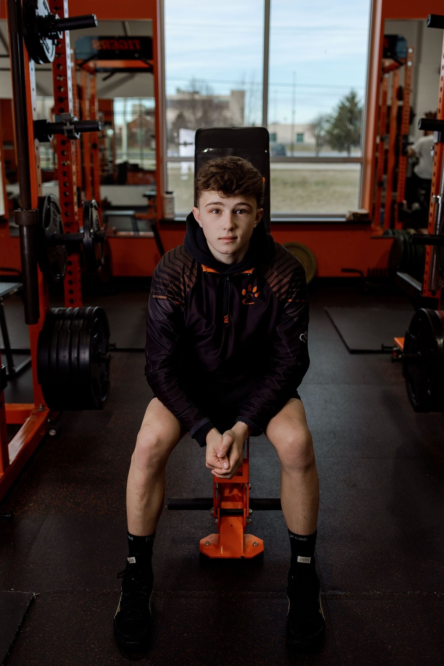 Person in dark athletic wear performs a series of stretching exercises in a red-accented fitness gym.