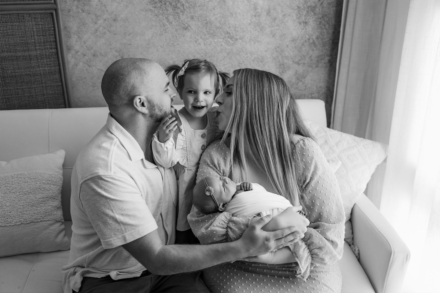 Family portrait session in a bright room with white decor and natural window lighting.