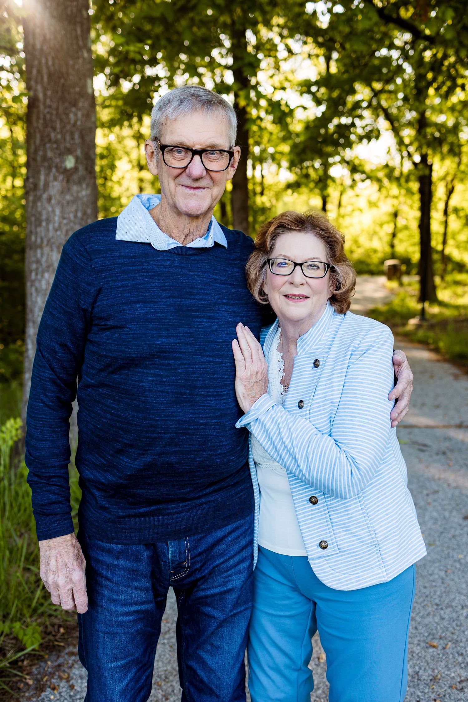 Senior couple embracing outdoors wearing coordinated blue and white sweaters.