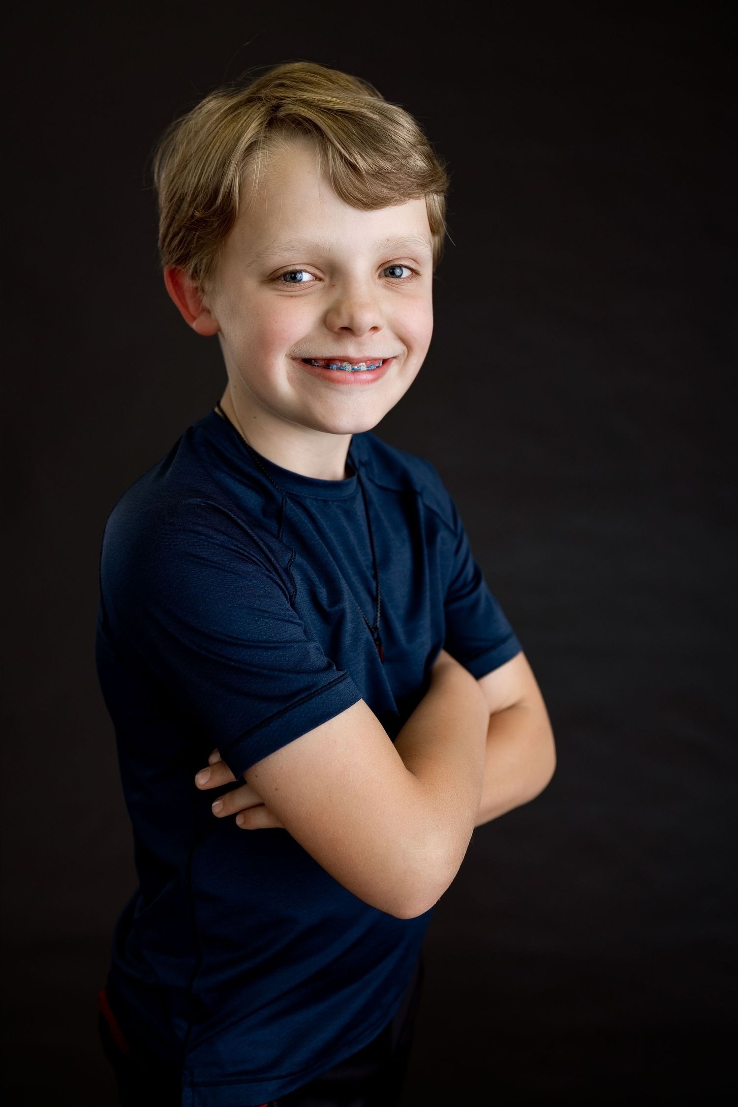Smiling young boy photographed against a dark backdrop during an Edwardsville milestone portrait session