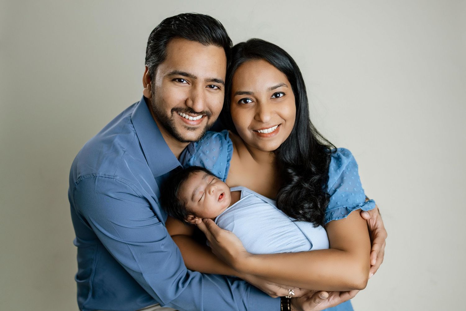 A loving family in coordinating blue outfits poses together for a series of intimate portrait photographs.