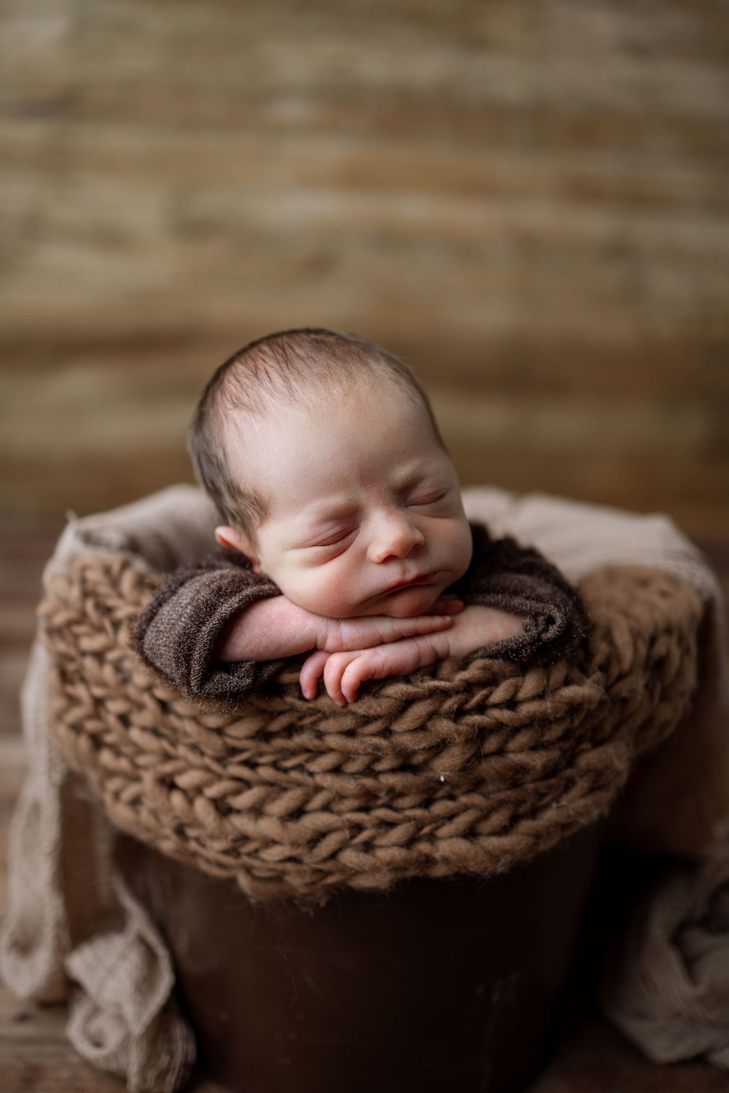 Collection of newborn photography shots with sleeping baby nestled in chunky brown knitted wrap.