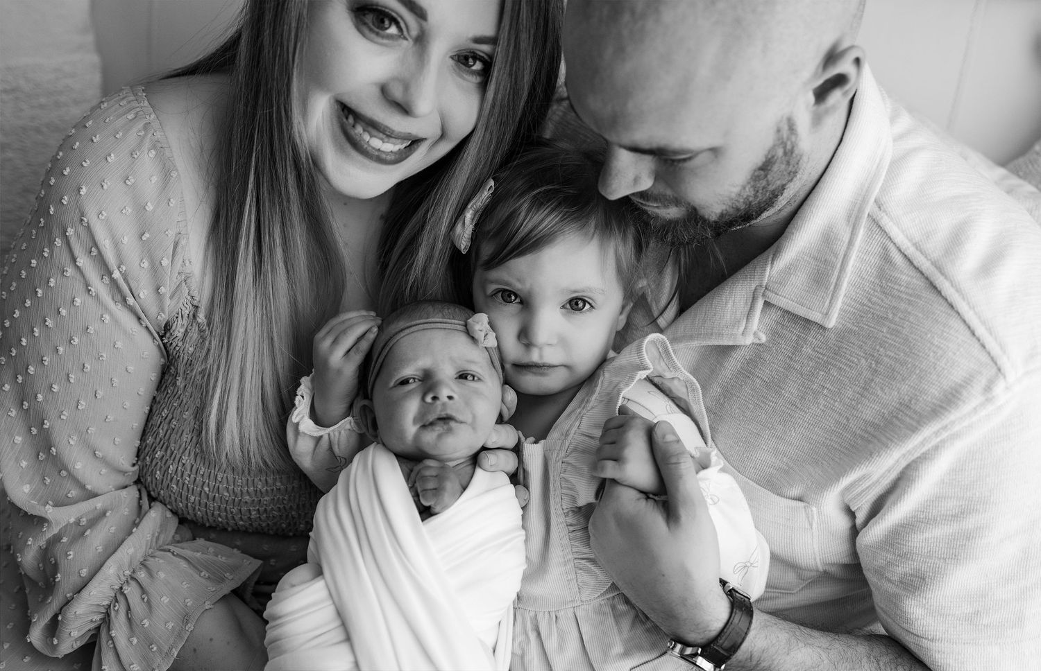 A series of intimate black and white family photos showing tender moments between parents and their young child.