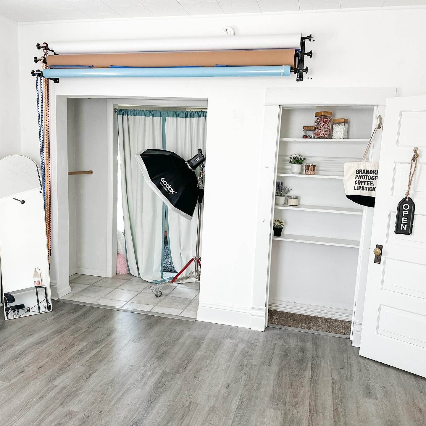 Photography studio setup with backdrop stand, lighting equipment and white decor.