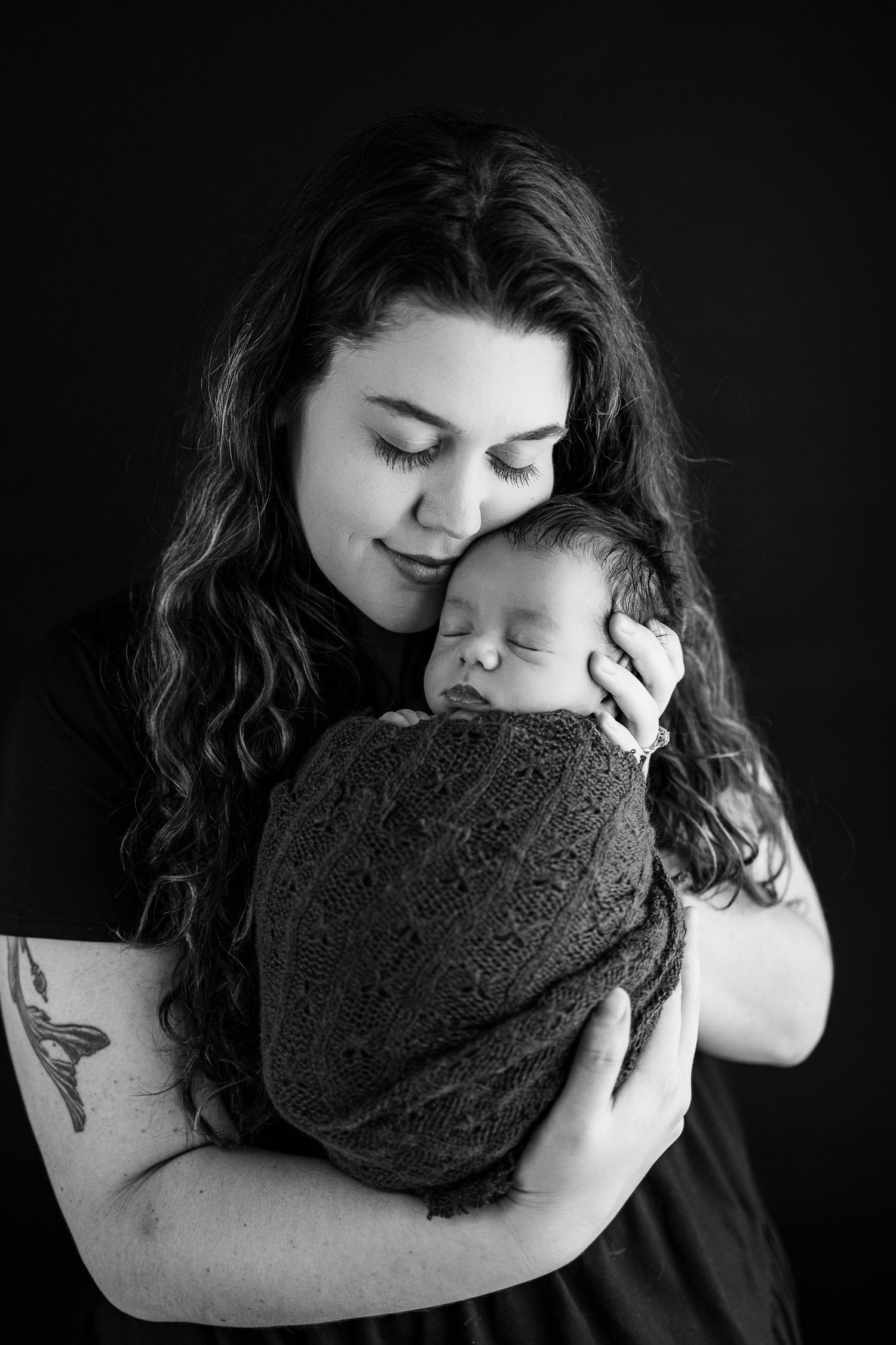 A series of intimate black and white photographs showing a tender embrace between parent and child in low-key lighting.