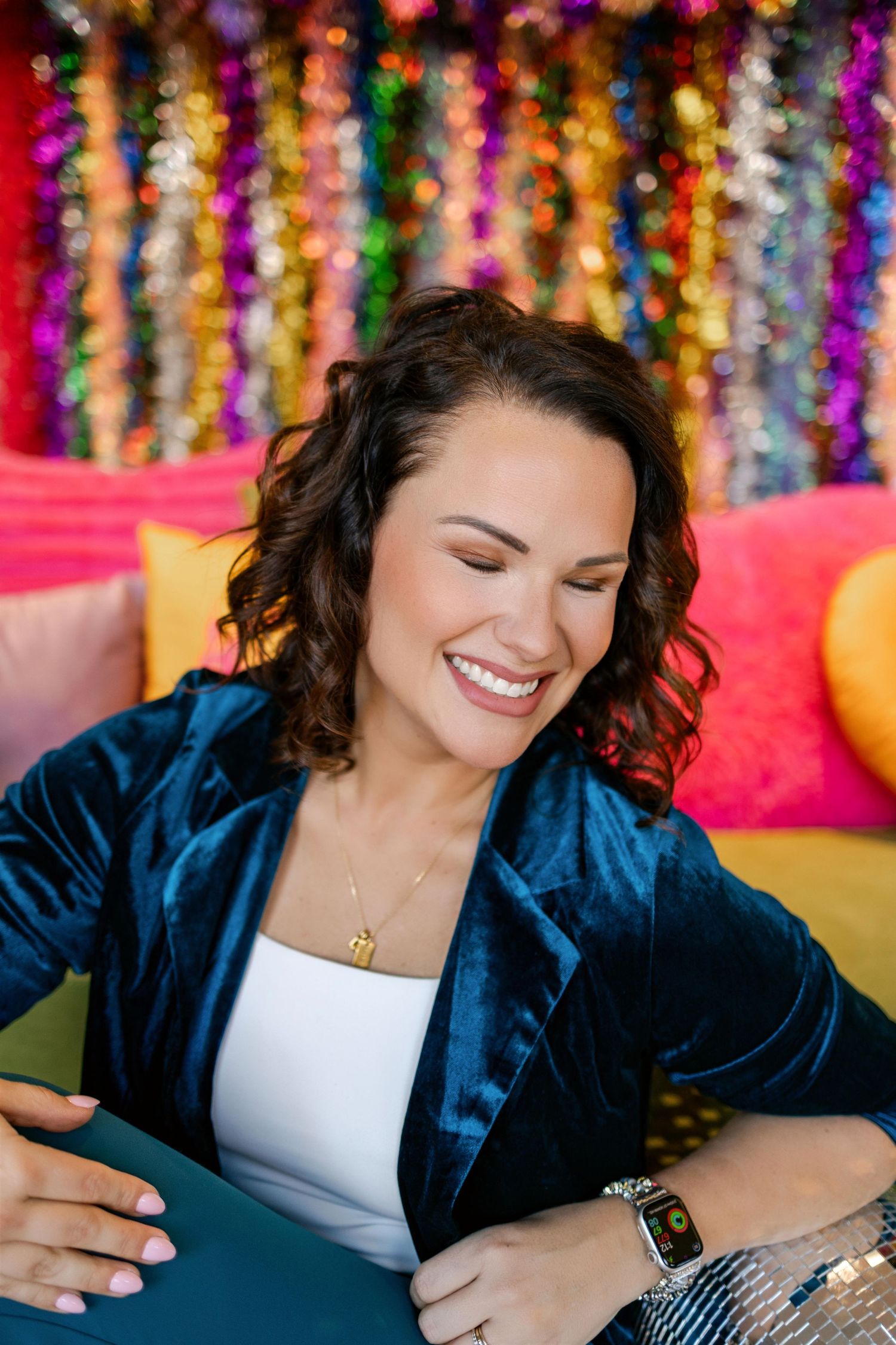 Vibrant brand photos with colorful tinsel backdrop and navy blazer in studio setting.