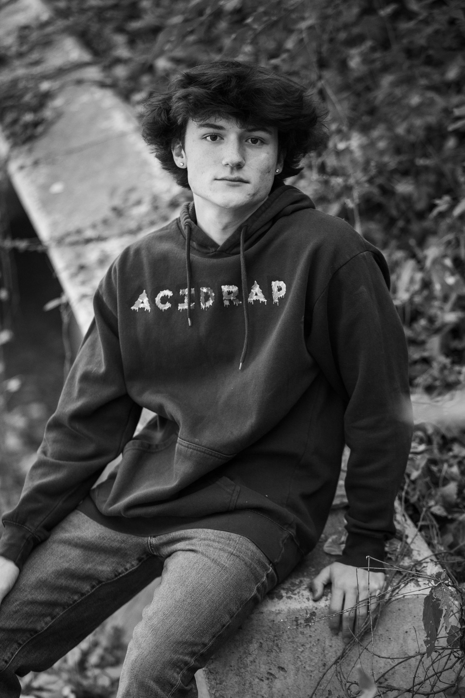 Teen wearing black Astrolab hoodie posing outdoors in black and white photo.
