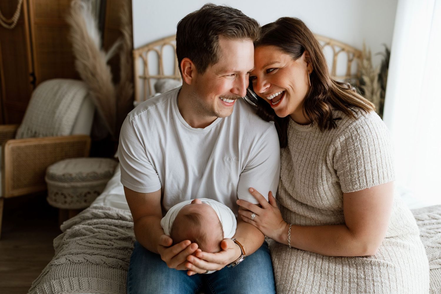 Parents smiling together while holding their newborn during a family photography session at Tara Lee Photography in Edwardsville, Illinois