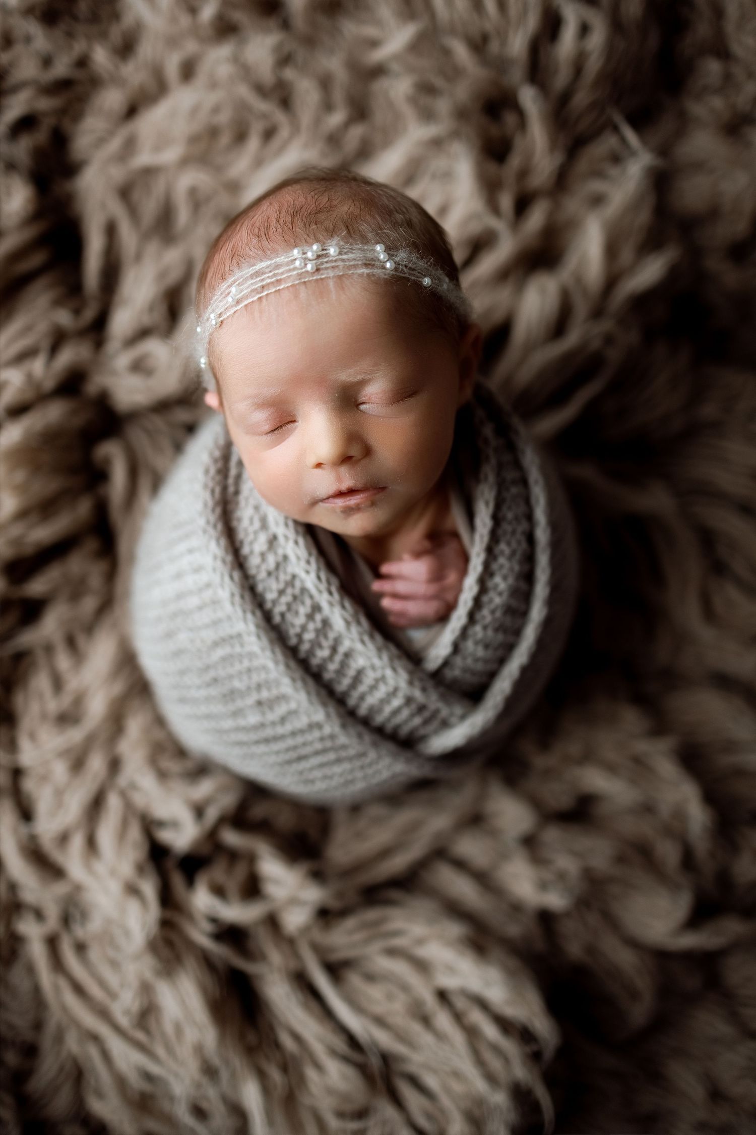 Newborn photography series showing baby wrapped in gray knit blanket on textured fur backdrop.