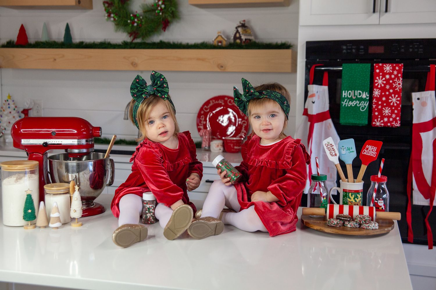 Holiday scene with red and white Christmas decorations displayed on white furniture with stockings and festive accents.
