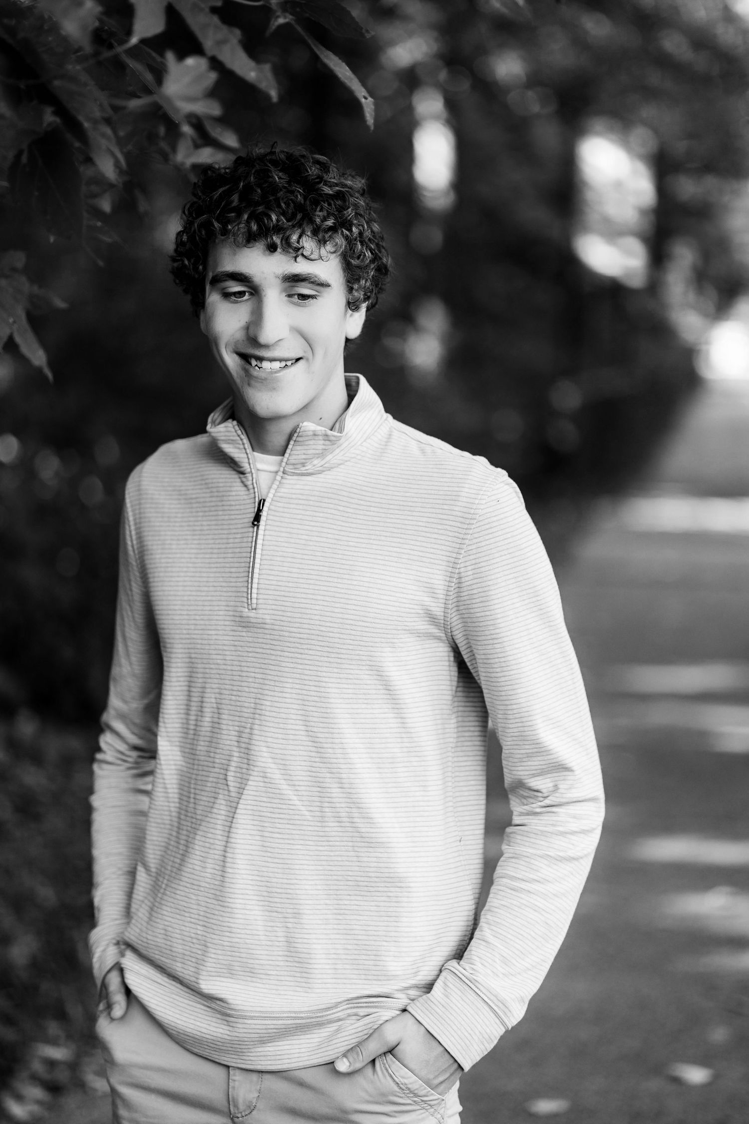 Black and white portrait of someone in a light colored sweater against a blurred outdoor background.